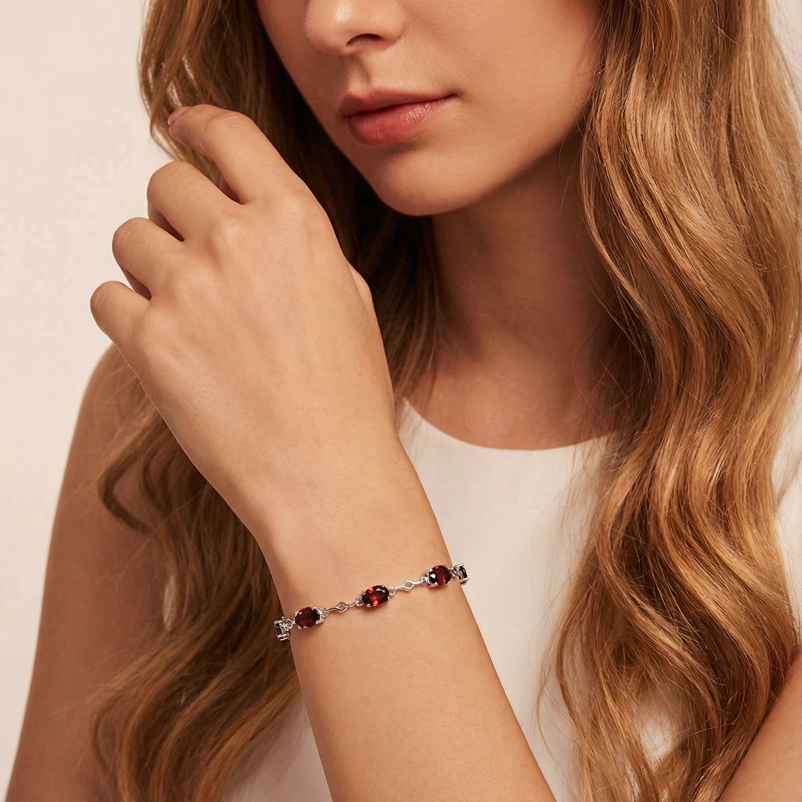 Valora S925 sterling silver station bracelet with oval red simulated garnets worn on a model's wrist with a white top.