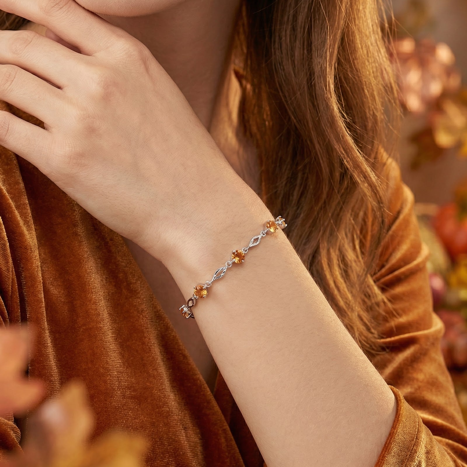 Close-up of the sterling silver Zenara station bracelet with honeyed simulated topaz stones worn on a woman's wrist.