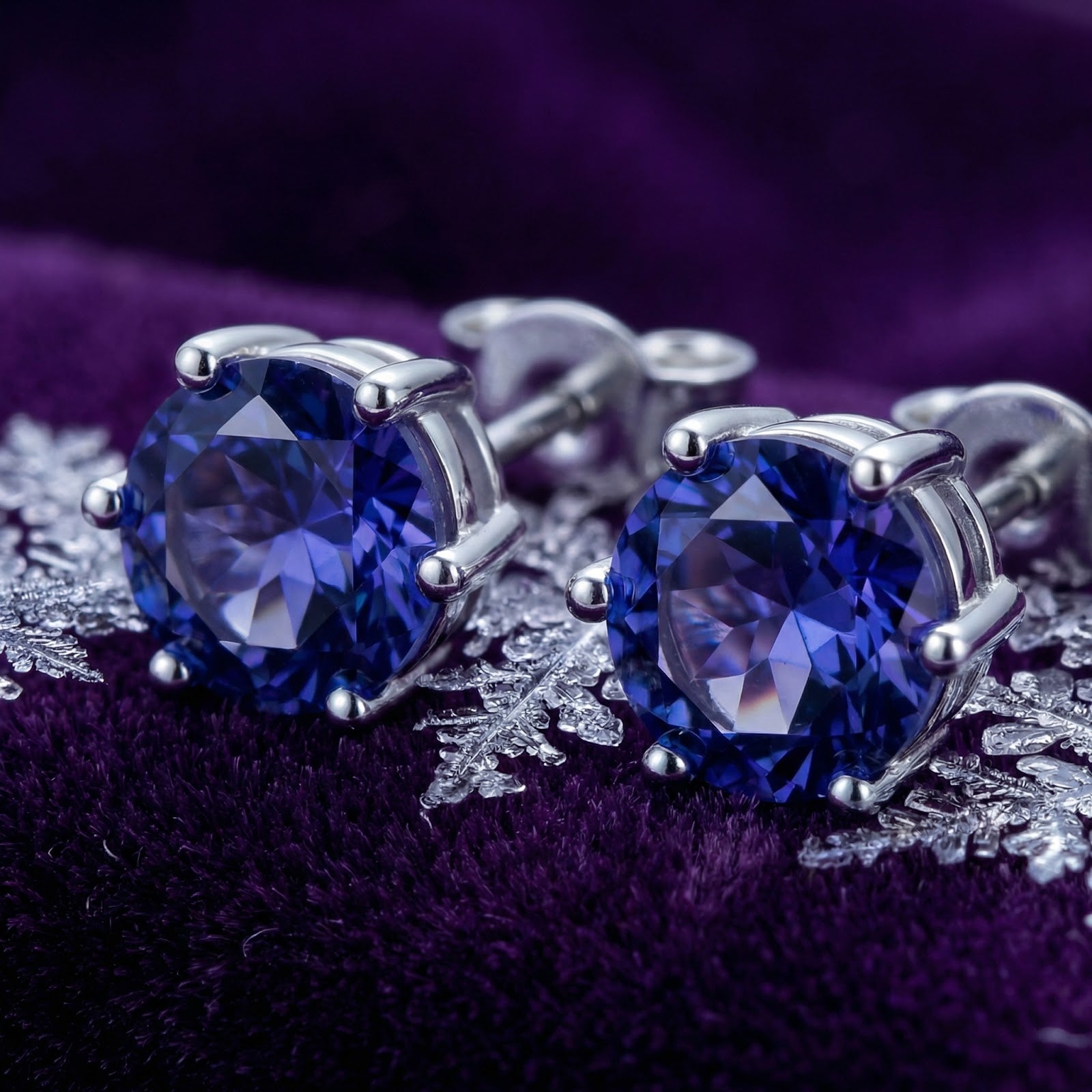 Macro view of round cut simulated tanzanite stones in sterling silver six-prong stud earring settings.