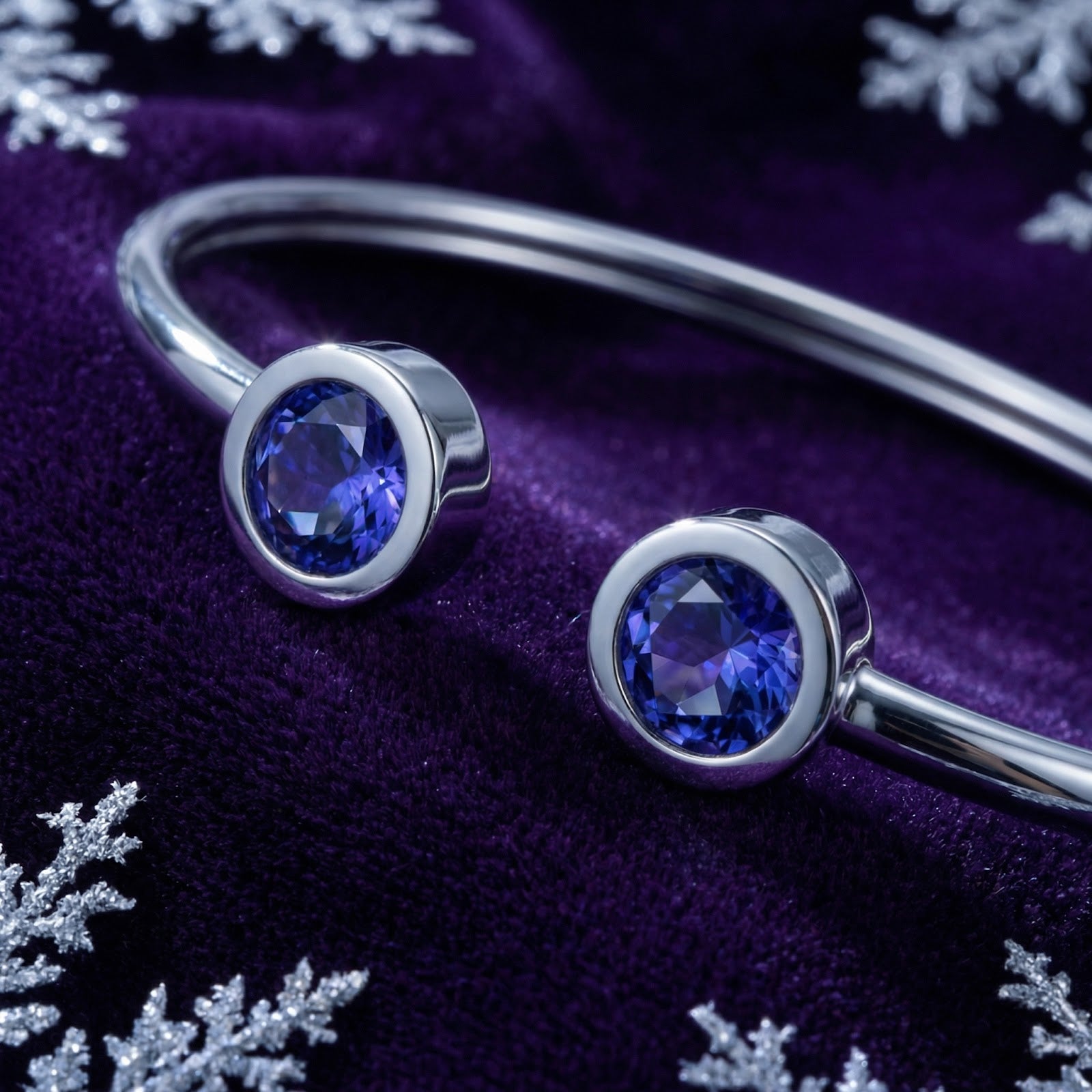 Close-up of round simulated tanzanite stones in a silver bezel bypass setting on a stainless steel cuff.