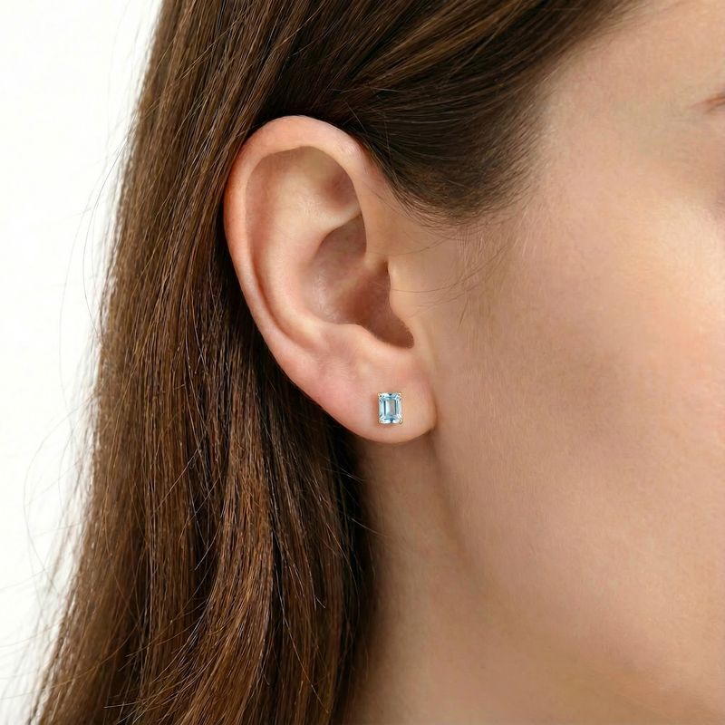 Model wearing a single baguette-cut simulated aquamarine stud earring in 18K gold vermeil.