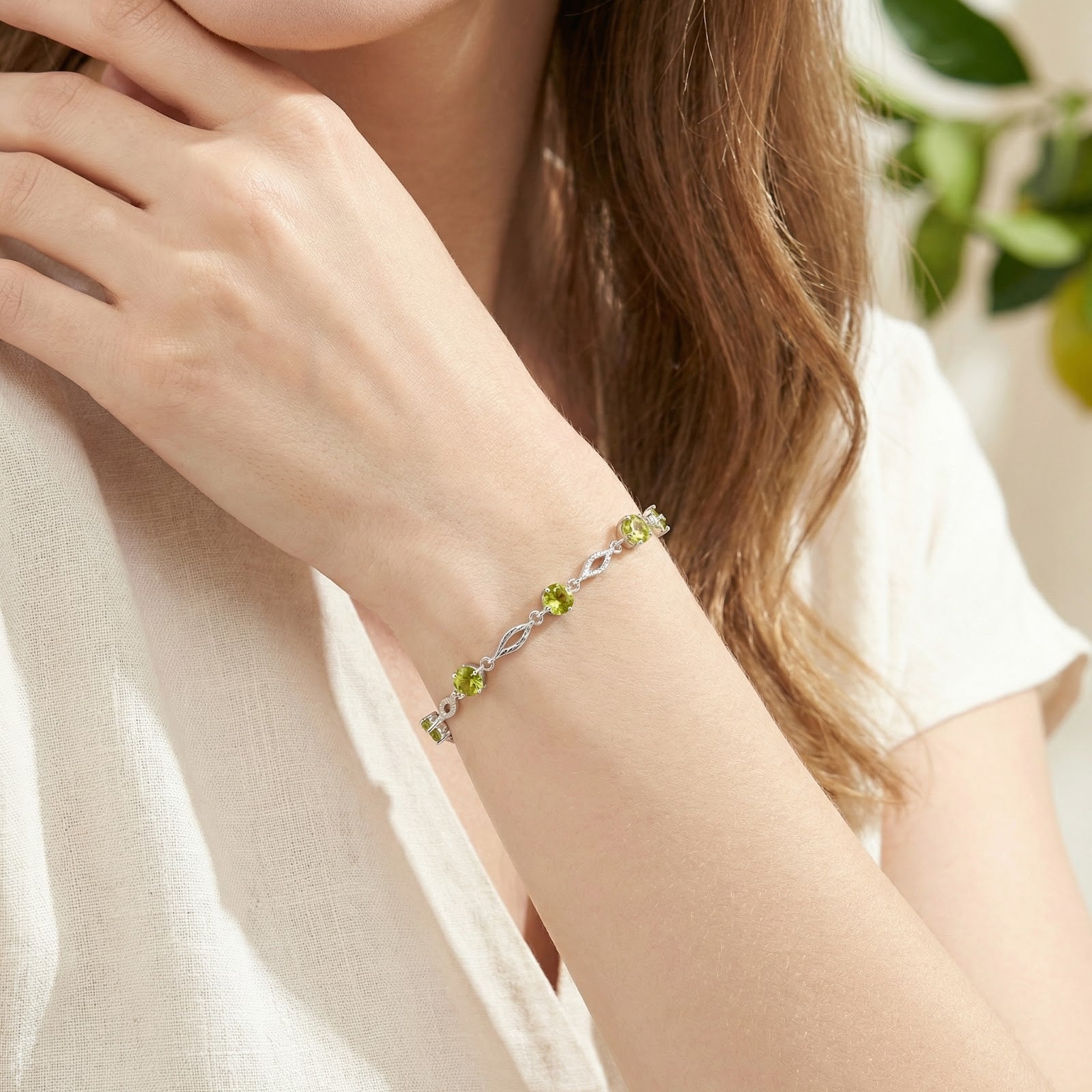 Clarisse S925 sterling silver station bracelet with round simulated peridot stones worn on a woman's wrist.