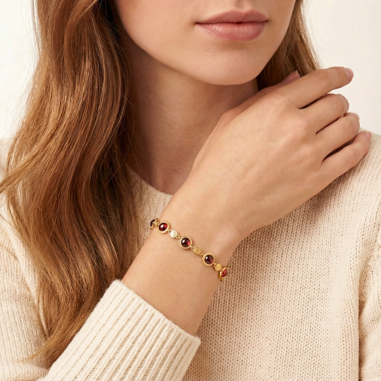 Woman wearing the Calyssa 18K gold vermeil station bracelet with deep red simulated garnets on her wrist.