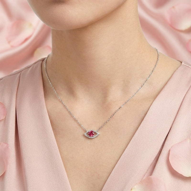 Round cut pink moissanite eye pendant in sterling silver worn on a woman's neck.