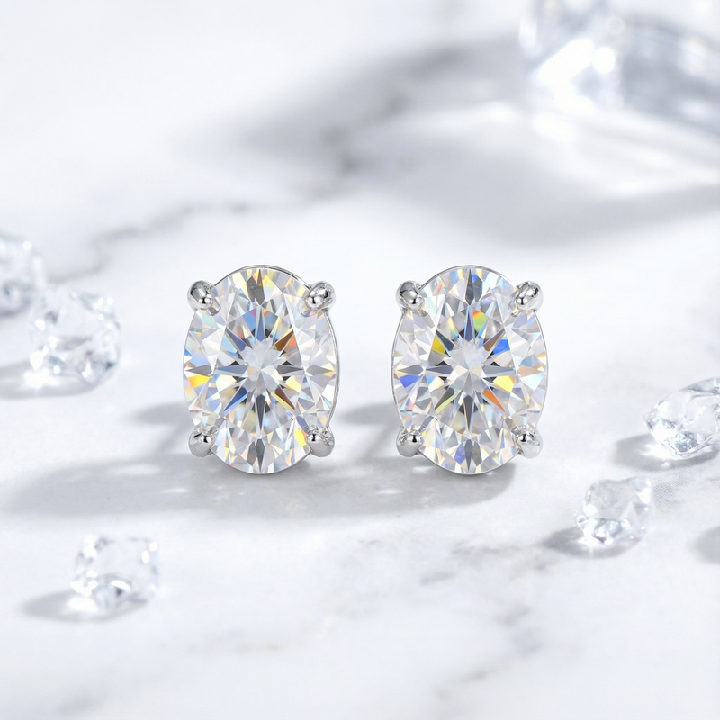 Front view of oval cut zirconia stud earrings in silver four-prong settings on a marble background.