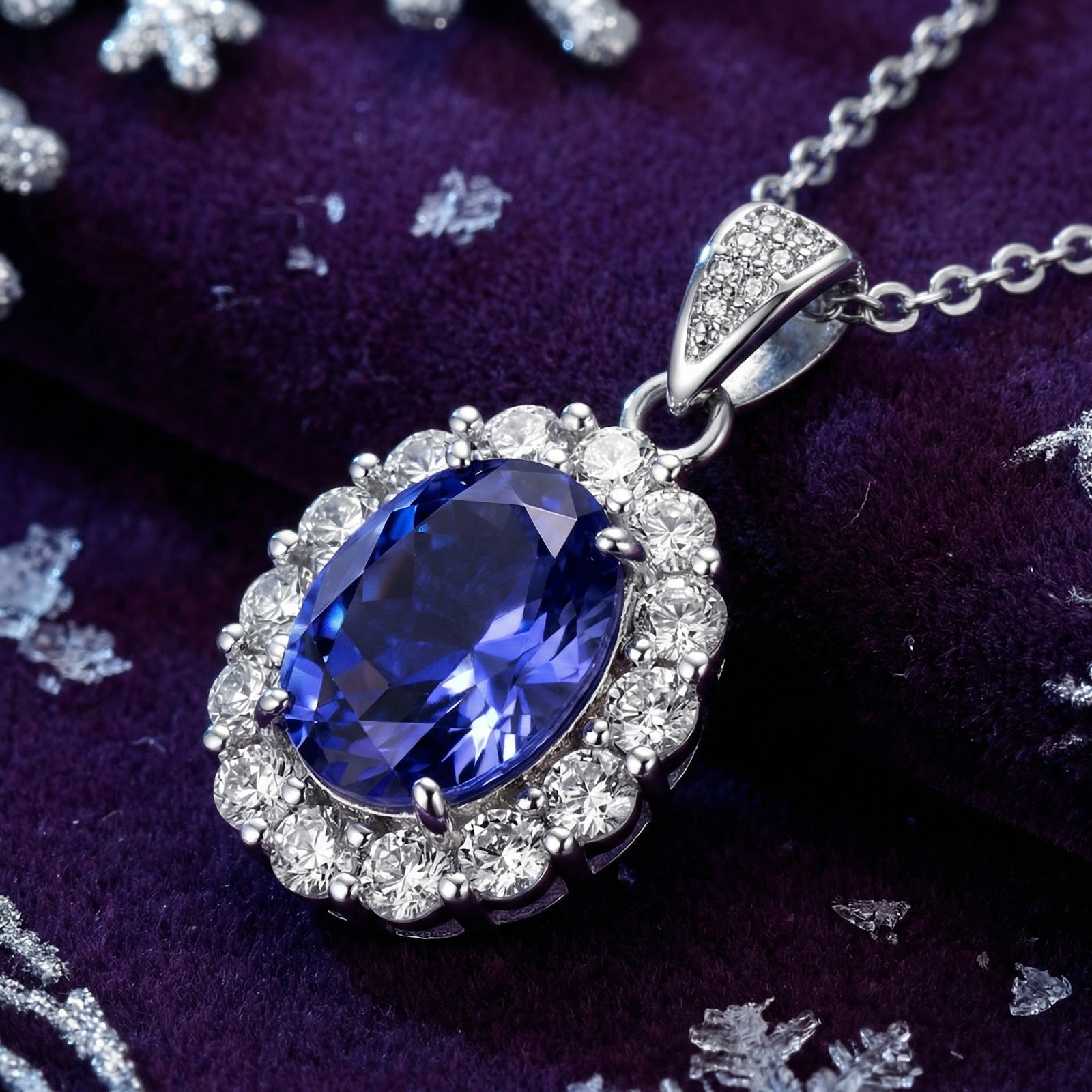 Oval simulated tanzanite halo necklace in sterling silver on purple velvet with decorative snowflakes.