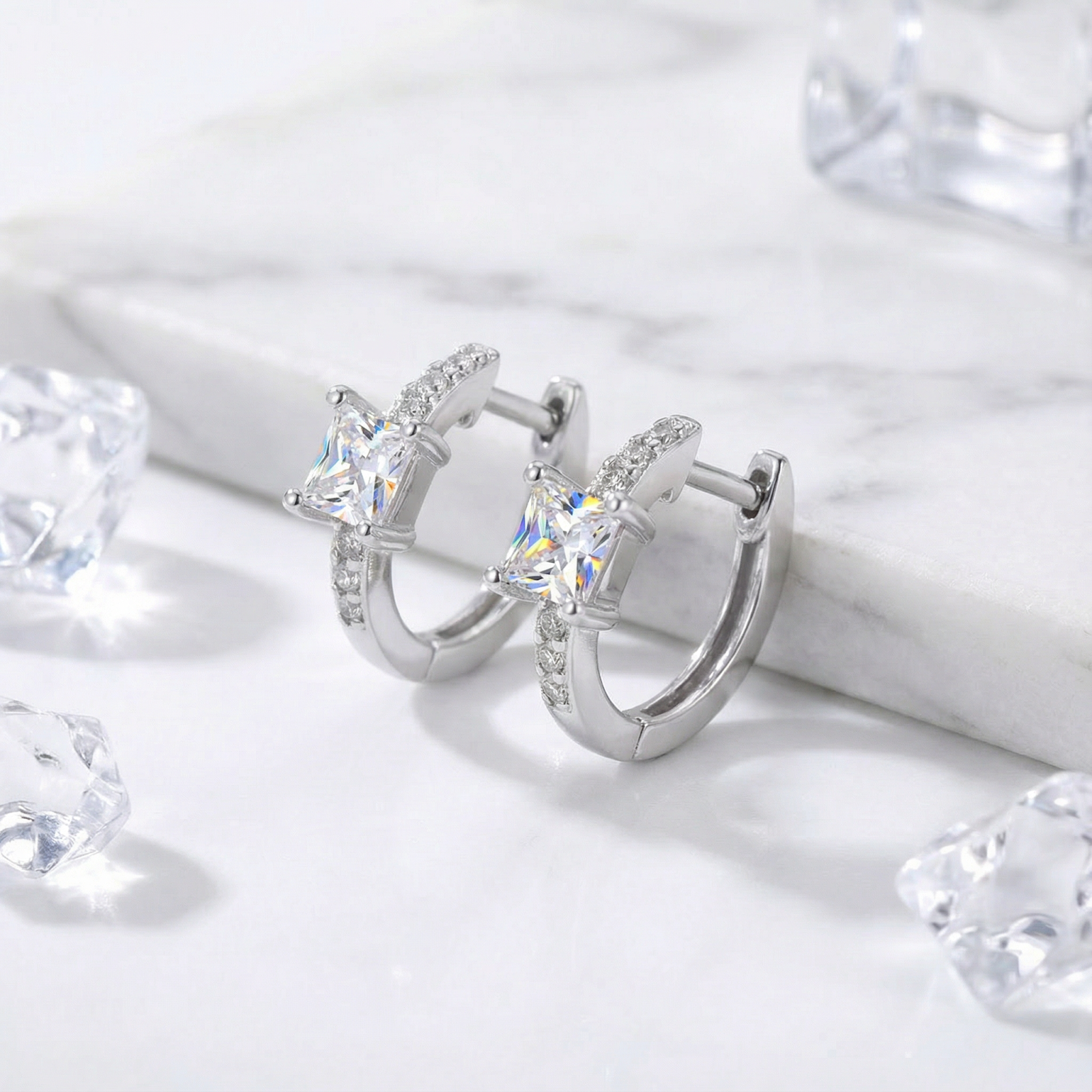 Side view of S925 sterling silver huggie earrings featuring princess-cut simulated diamonds on a marble background.