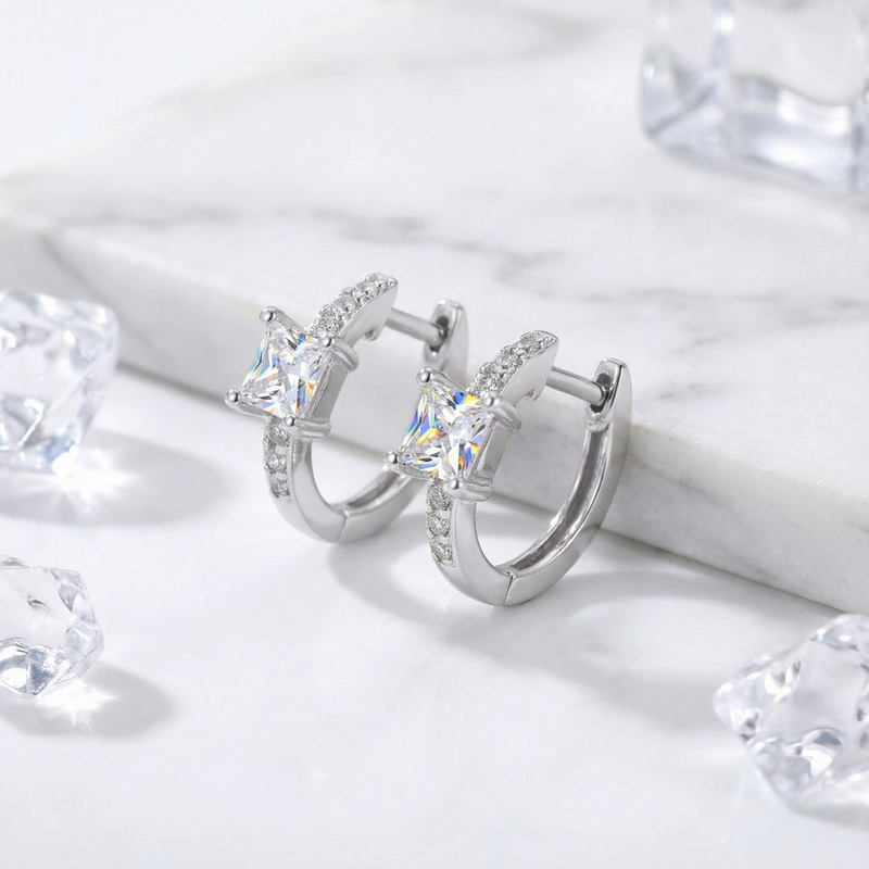 Side view of S925 sterling silver huggie earrings featuring princess-cut simulated diamonds on a marble background.