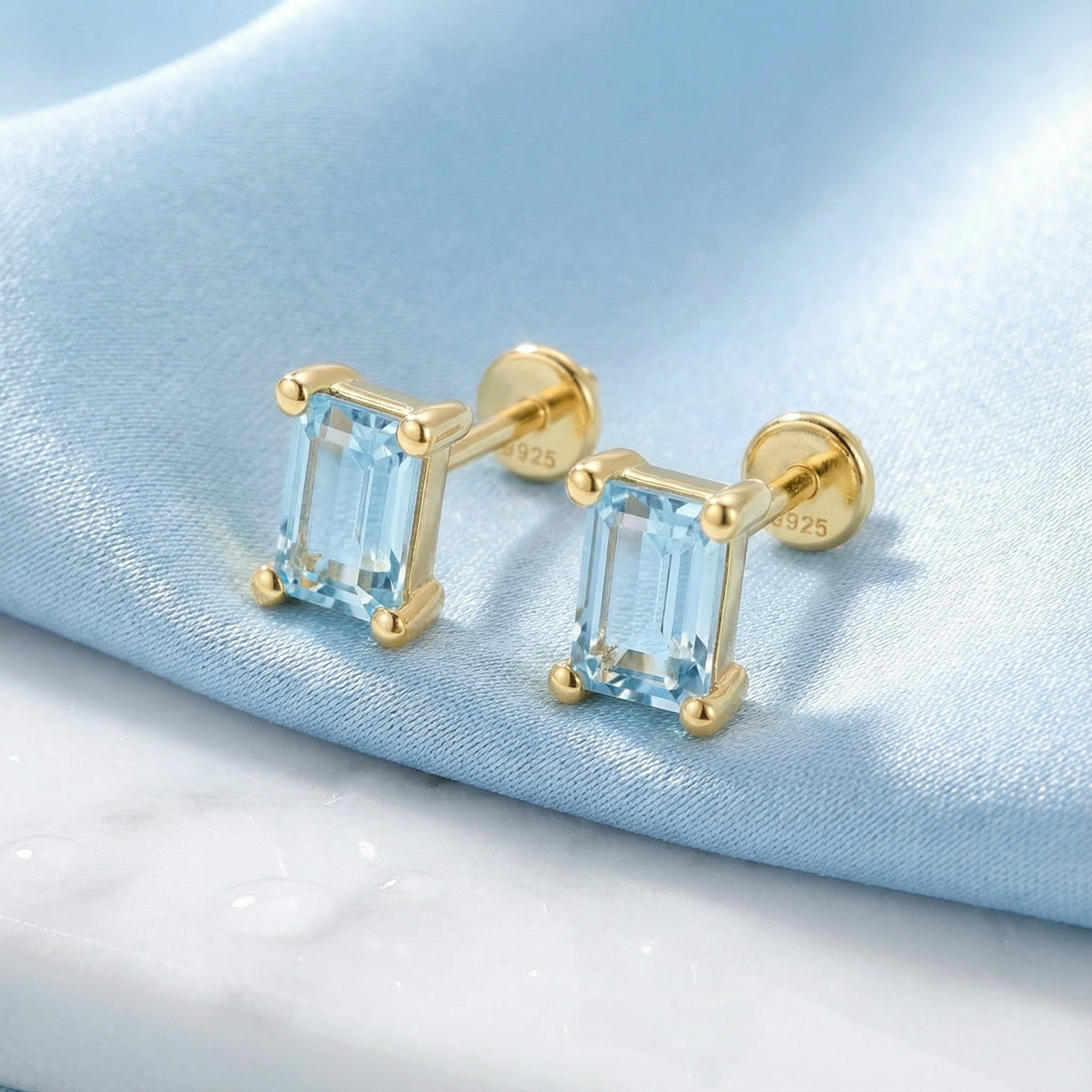 Macro view of baguette-cut simulated aquamarine earrings in 18K gold vermeil showing S925 sterling silver hallmark.