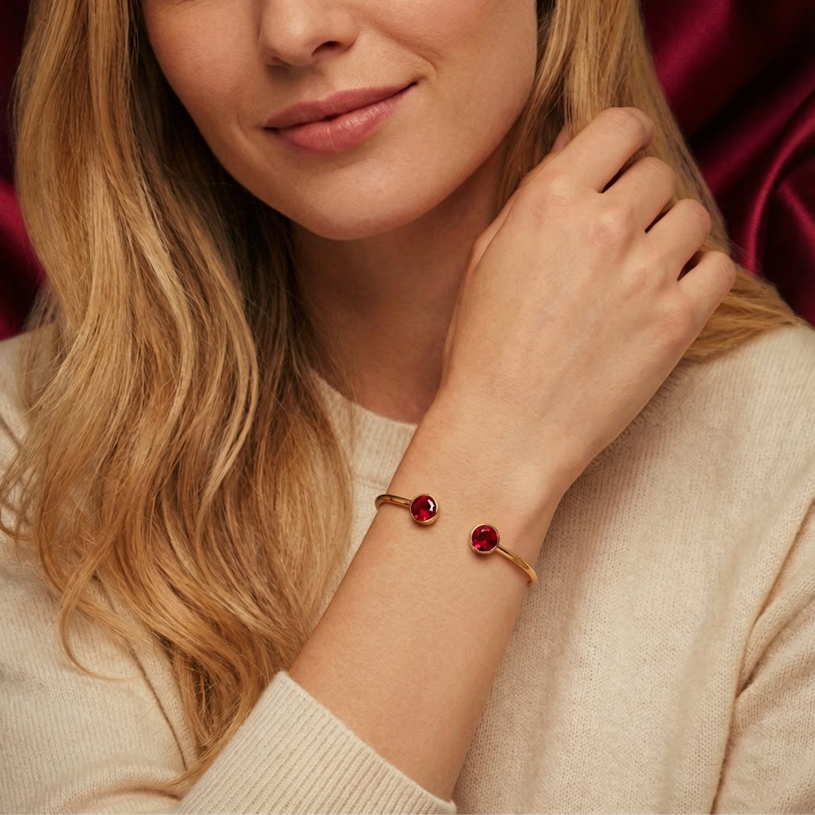 Model wearing the gold stainless steel Selenis bangle with round red simulated rubies on her wrist.