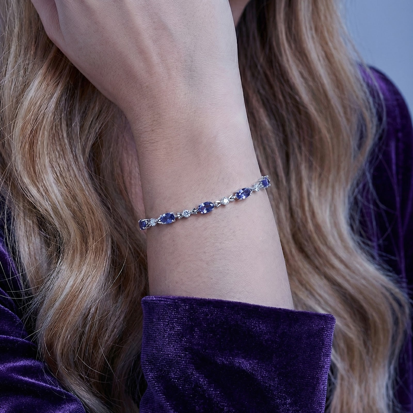 Sterling silver bracelet with oval blue-violet simulated tanzanite stones worn on a woman's wrist.
