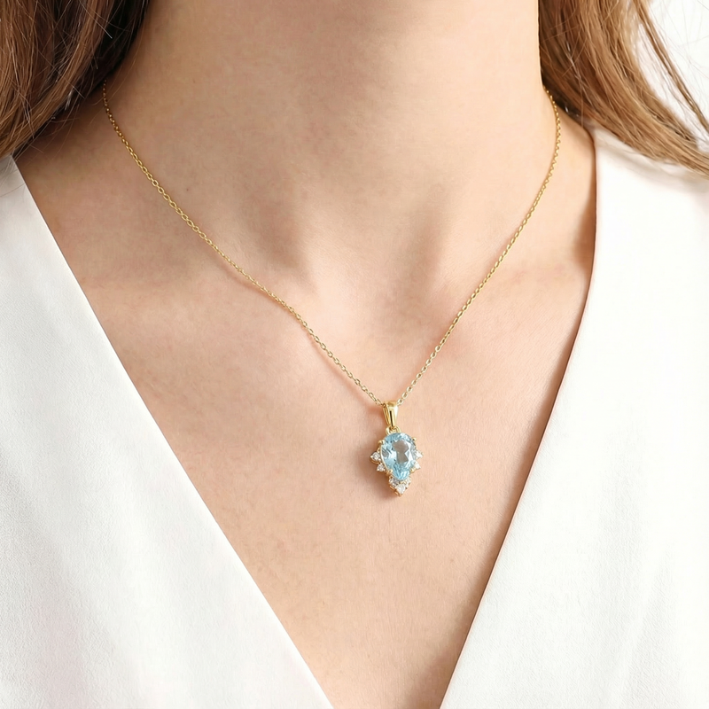Woman wearing the Aetheria pear cut simulated aquamarine necklace in 18K gold vermeil.