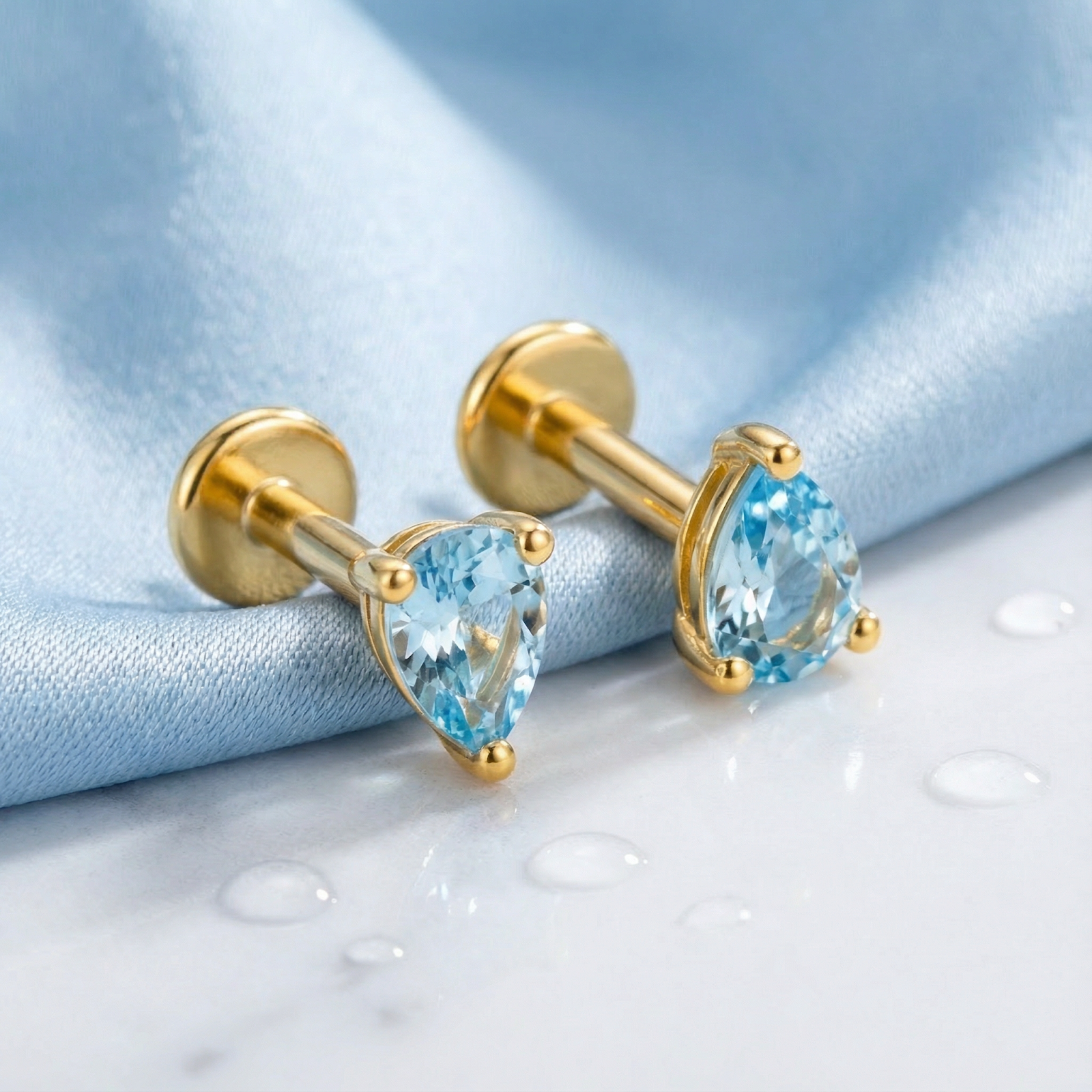 Macro shot of pear cut simulated aquamarine stones in 18K gold vermeil teardrop earring settings.