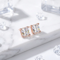 Princess cut zirconia stud earrings in 18K rose gold vermeil on a white marble surface with crystal accents.