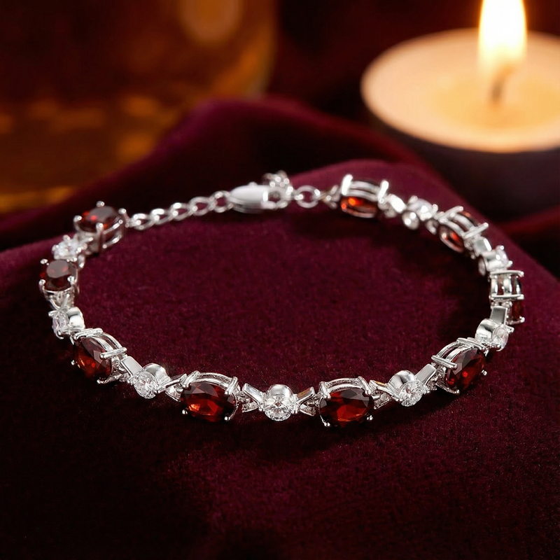 Detail view of oval cut simulated red garnets and silver settings on the Melora tennis bracelet.