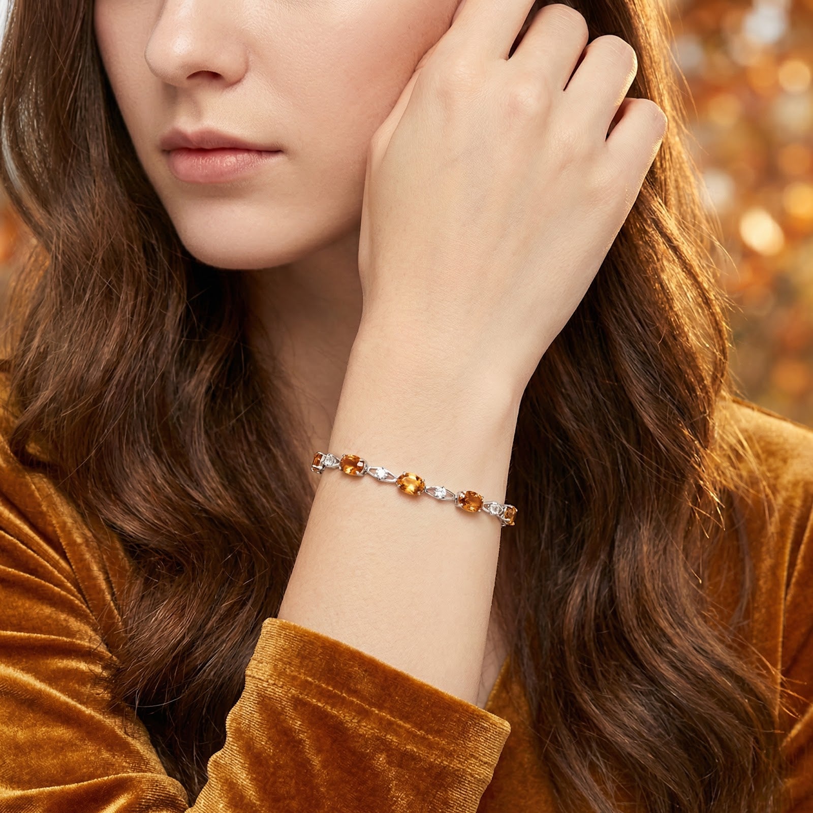 Woman wearing the silver wave bracelet with honeyed simulated topaz stones on her wrist.