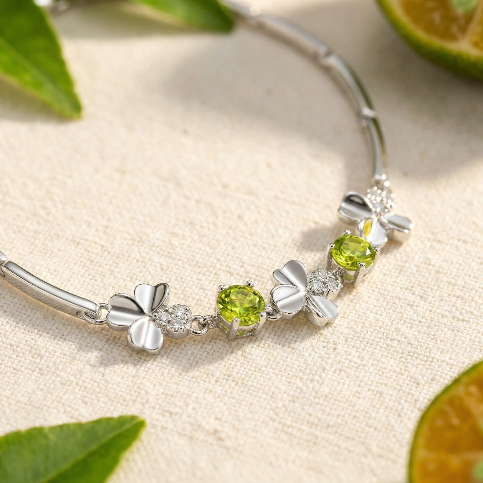 Macro view of precision-cut round peridot stones and silver clover charms on a sterling silver bracelet.