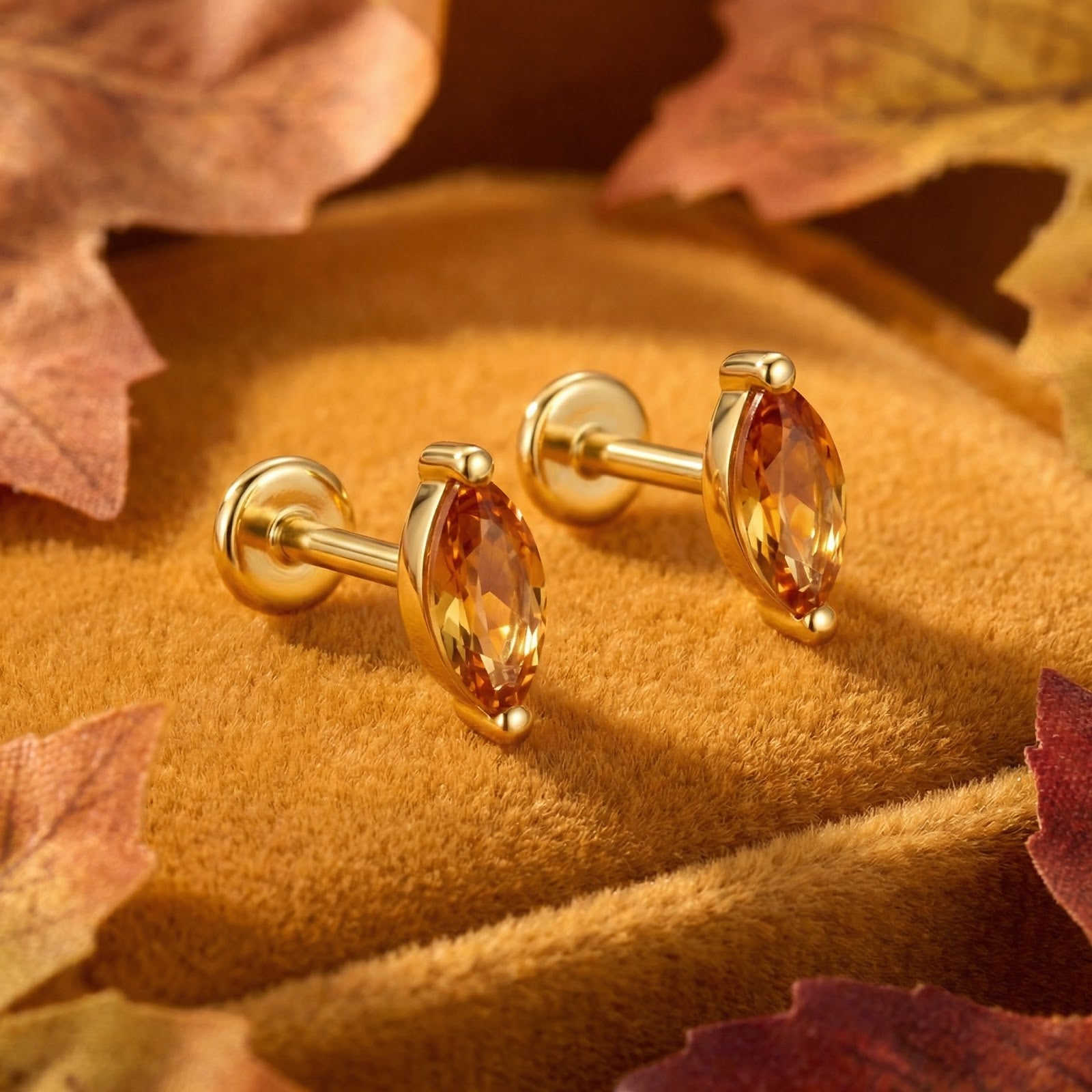 Marquise-cut simulated topaz earrings in 18K gold vermeil on a velvet surface with autumn leaves.