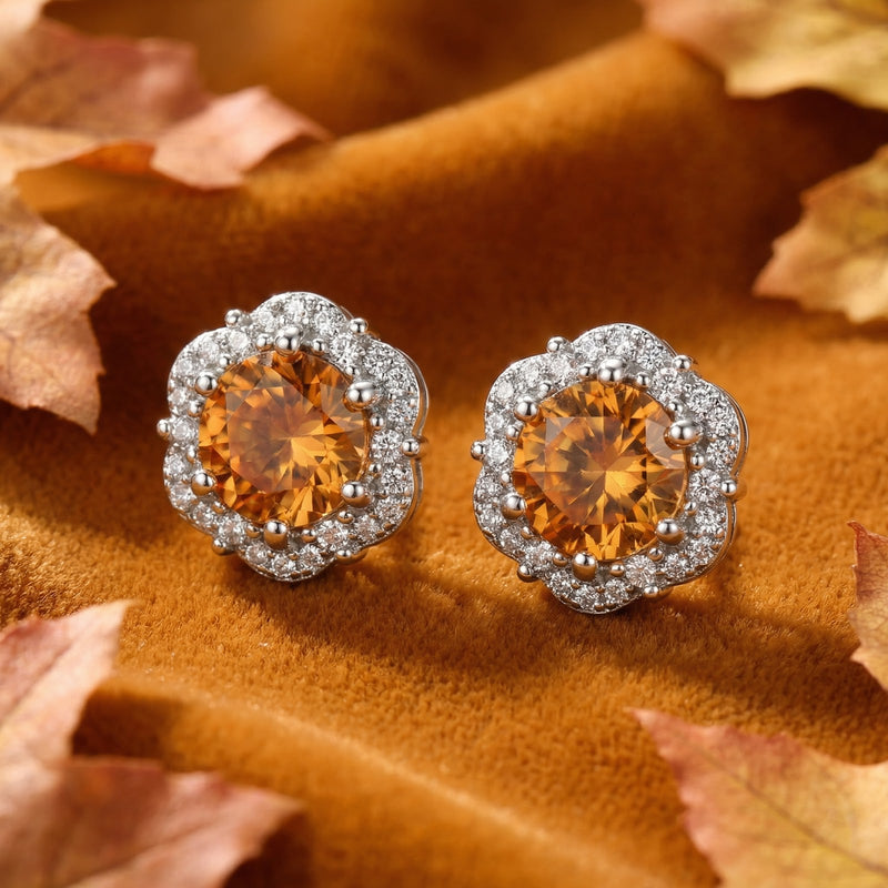 Angled view of sterling silver halo stud earrings with round honey-colored simulated topaz on warm velvet fabric.