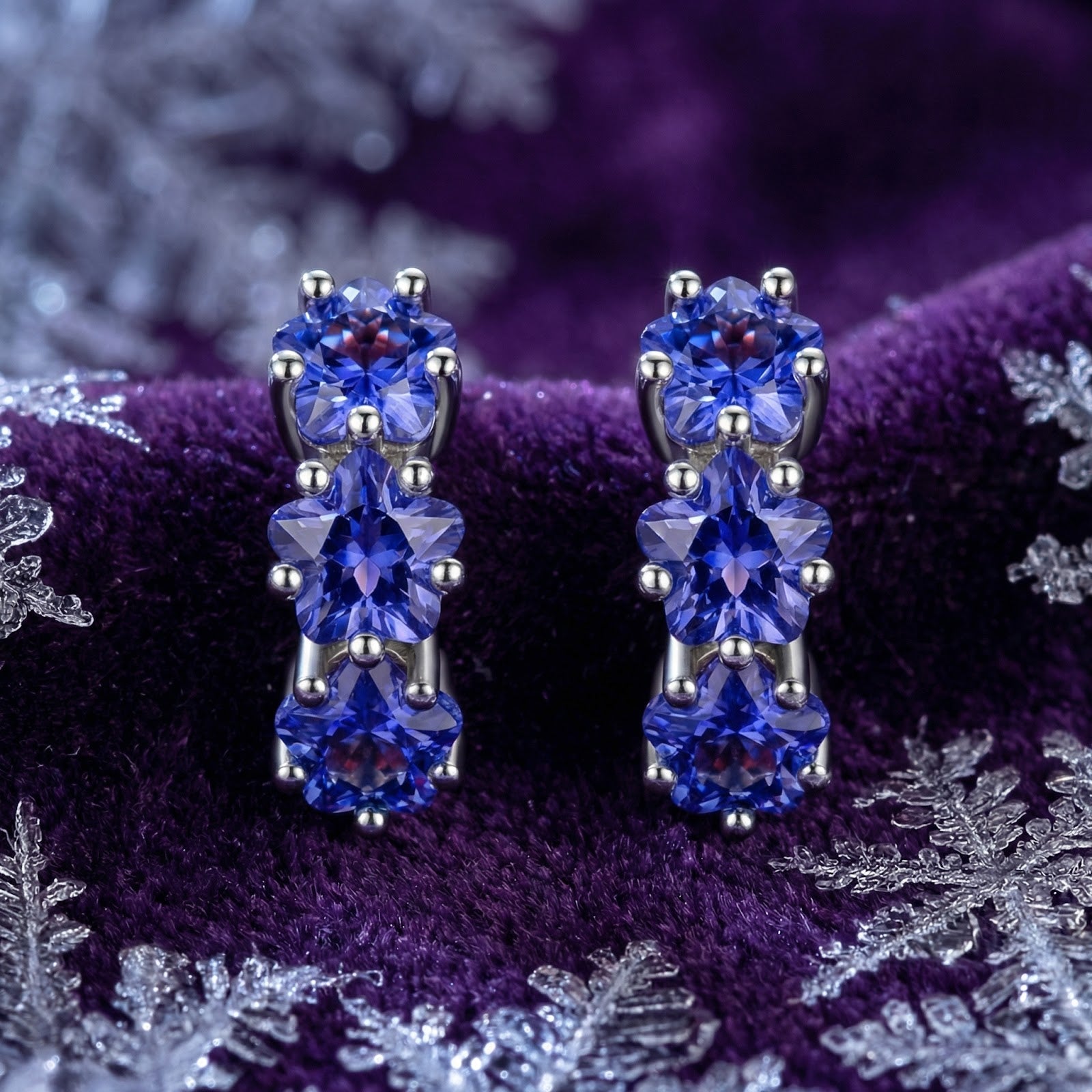 Front view of sterling silver star huggie earrings featuring three blue-violet simulated tanzanite stones.