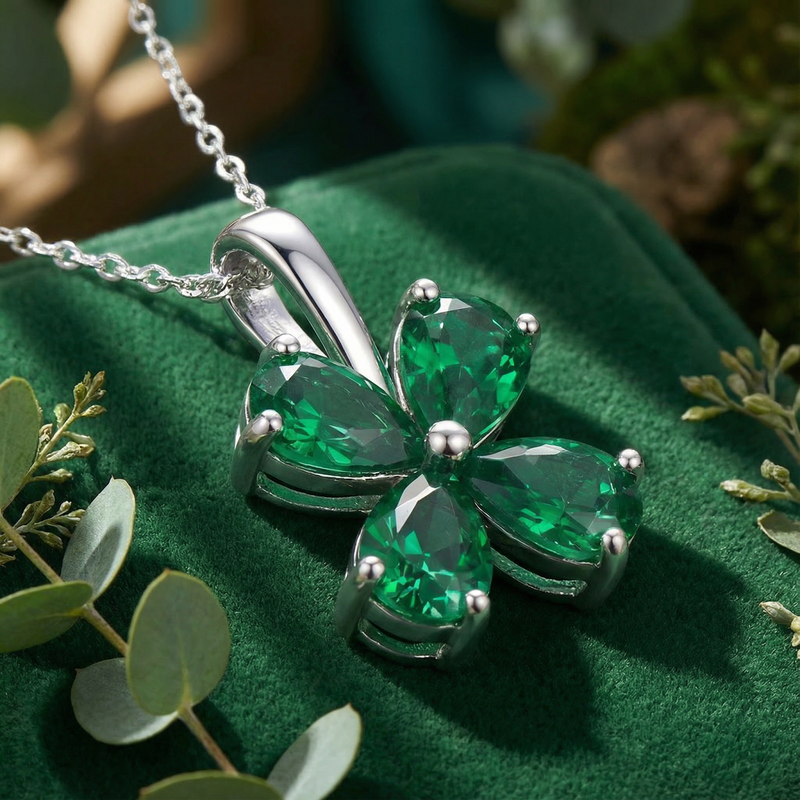 Close-up of a sterling silver clover pendant featuring four pear-cut simulated emeralds in a prong setting.