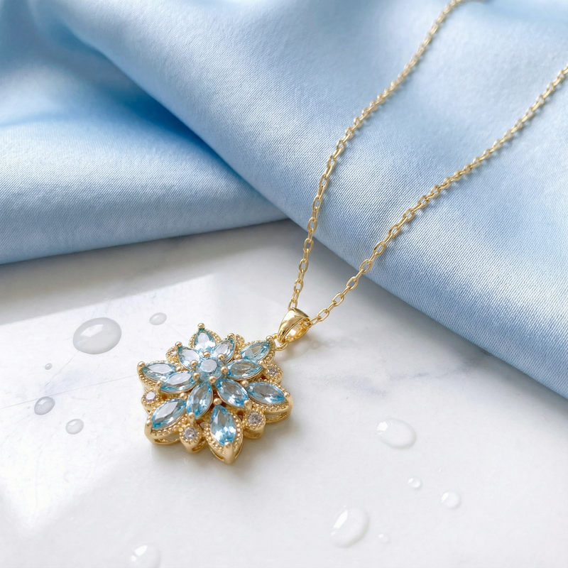 Detail view of the gold stainless steel flower pendant featuring marquise-cut simulated aquamarine stones.