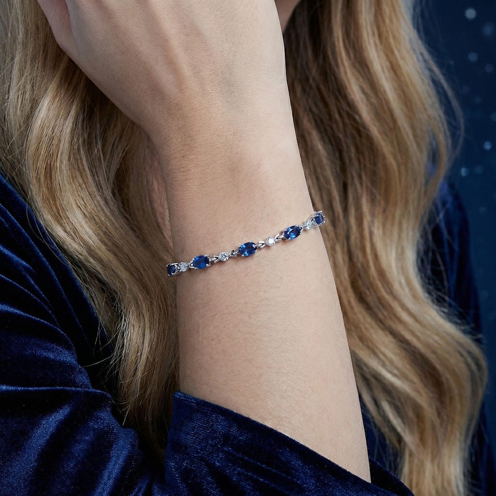 Marisara Oval simulated sapphire tennis bracelet in sterling silver worn on a woman's wrist.