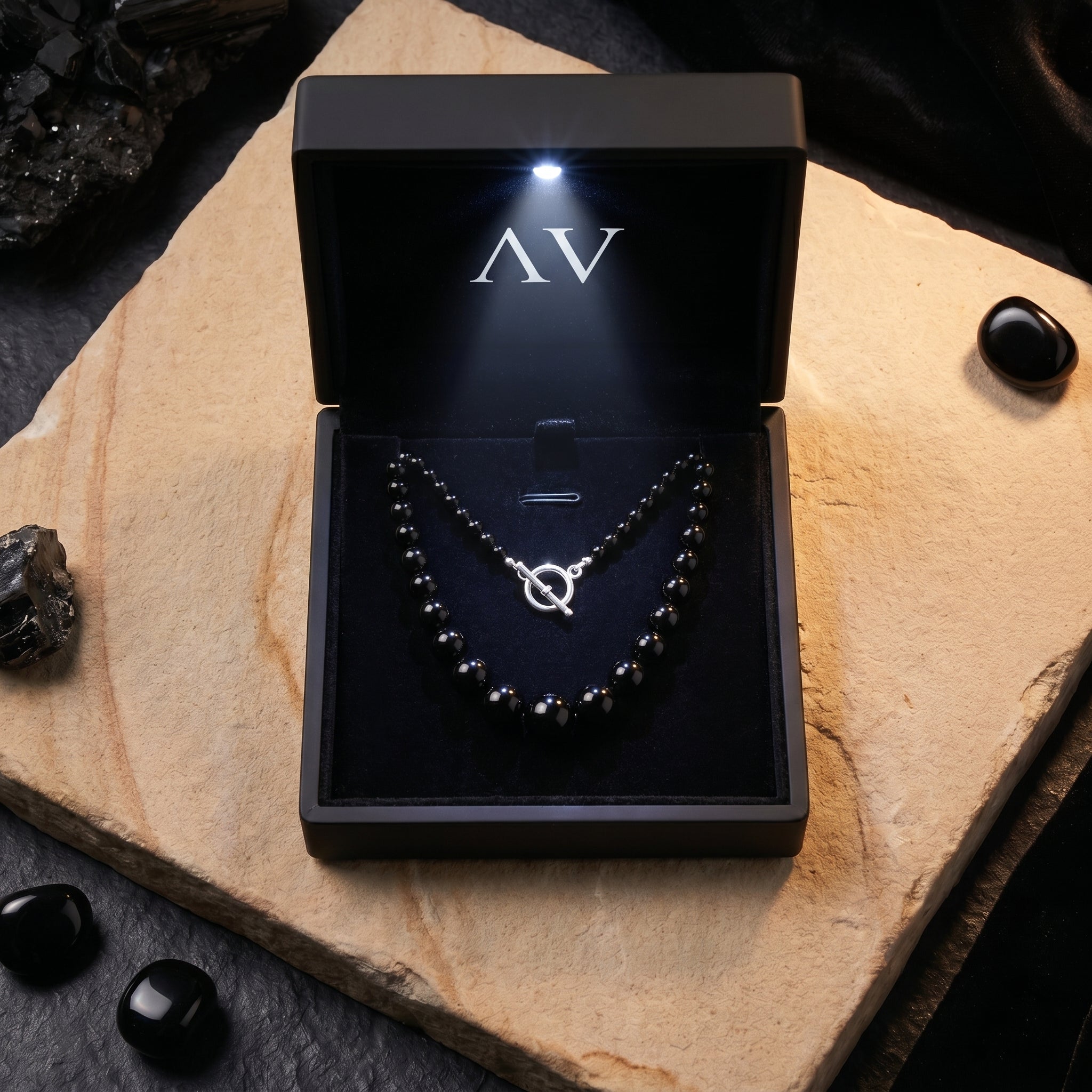 Graduated natural black onyx necklace with silver toggle clasp in a lighted black AV branded jewelry gift box.