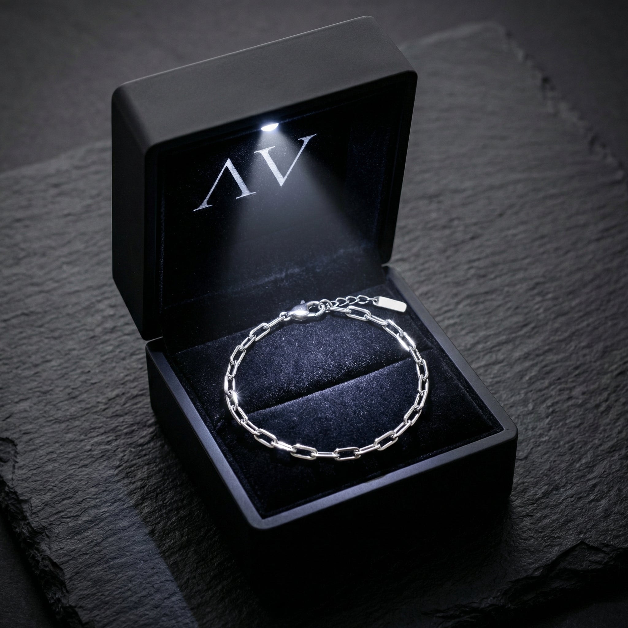 Silver stainless steel clip chain bracelet presented in a premium black LED-lit jewelry gift box.