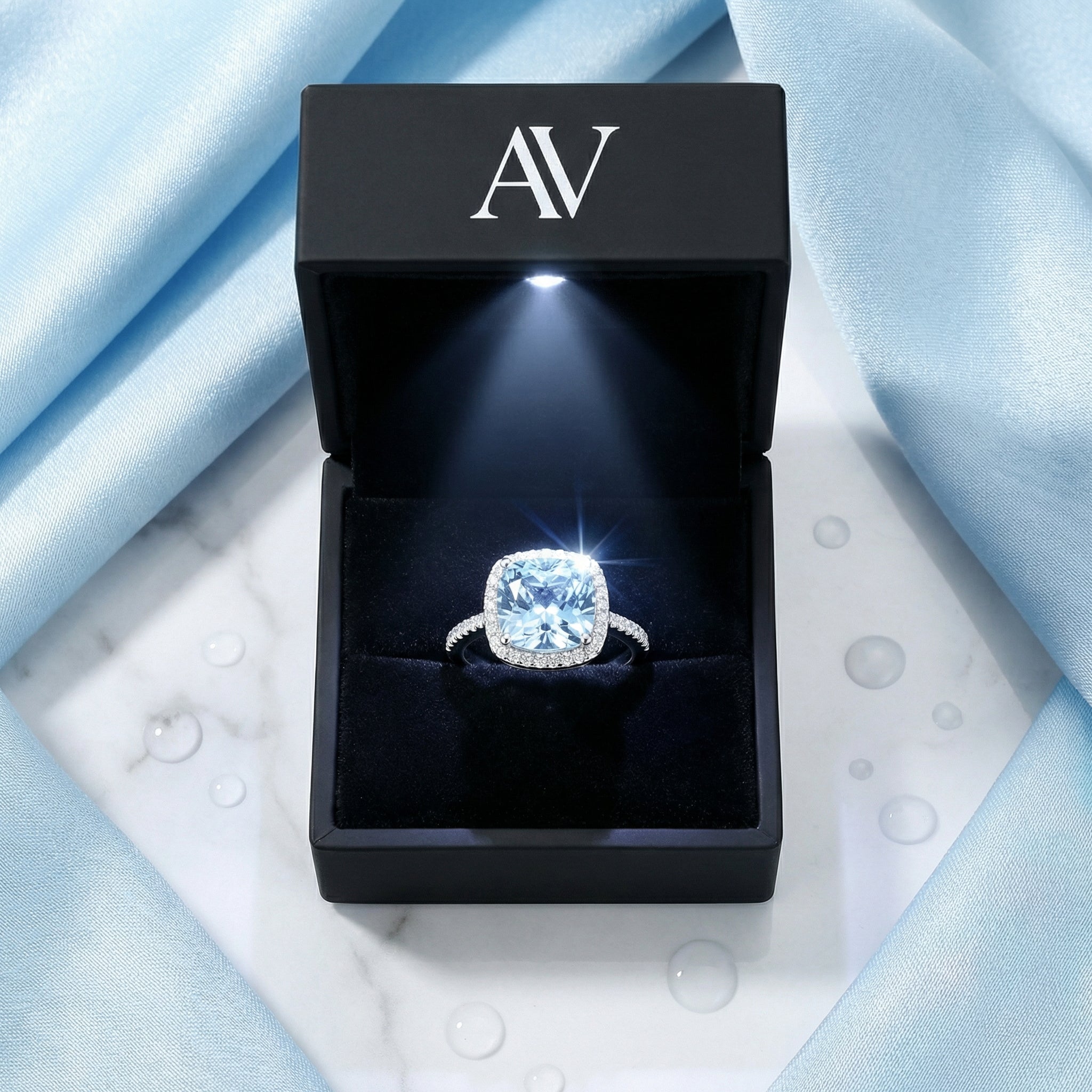 Simulated aquamarine sterling silver halo ring presented in a black LED-lit jewelry box.