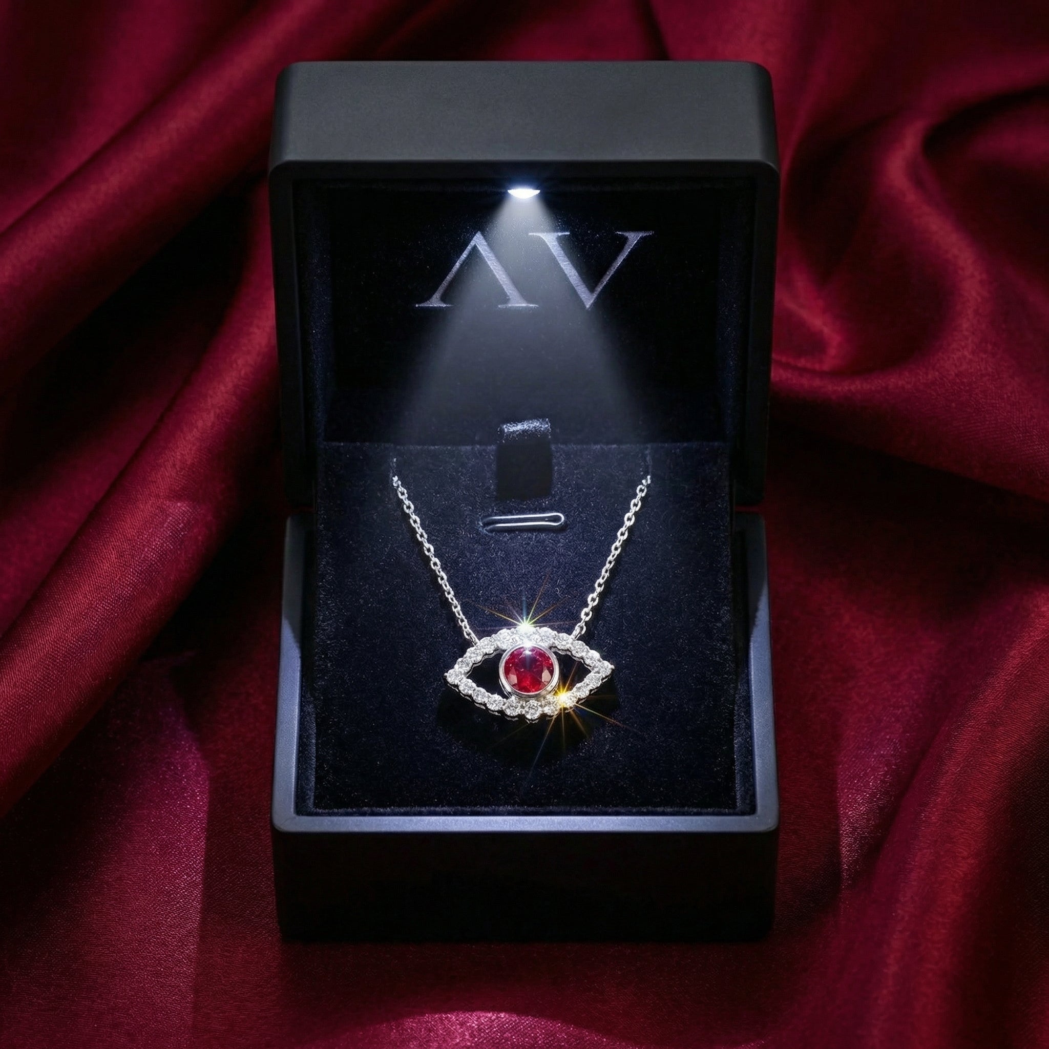 Red moissanite eye necklace in sterling silver showcased inside a black lighted jewelry box.