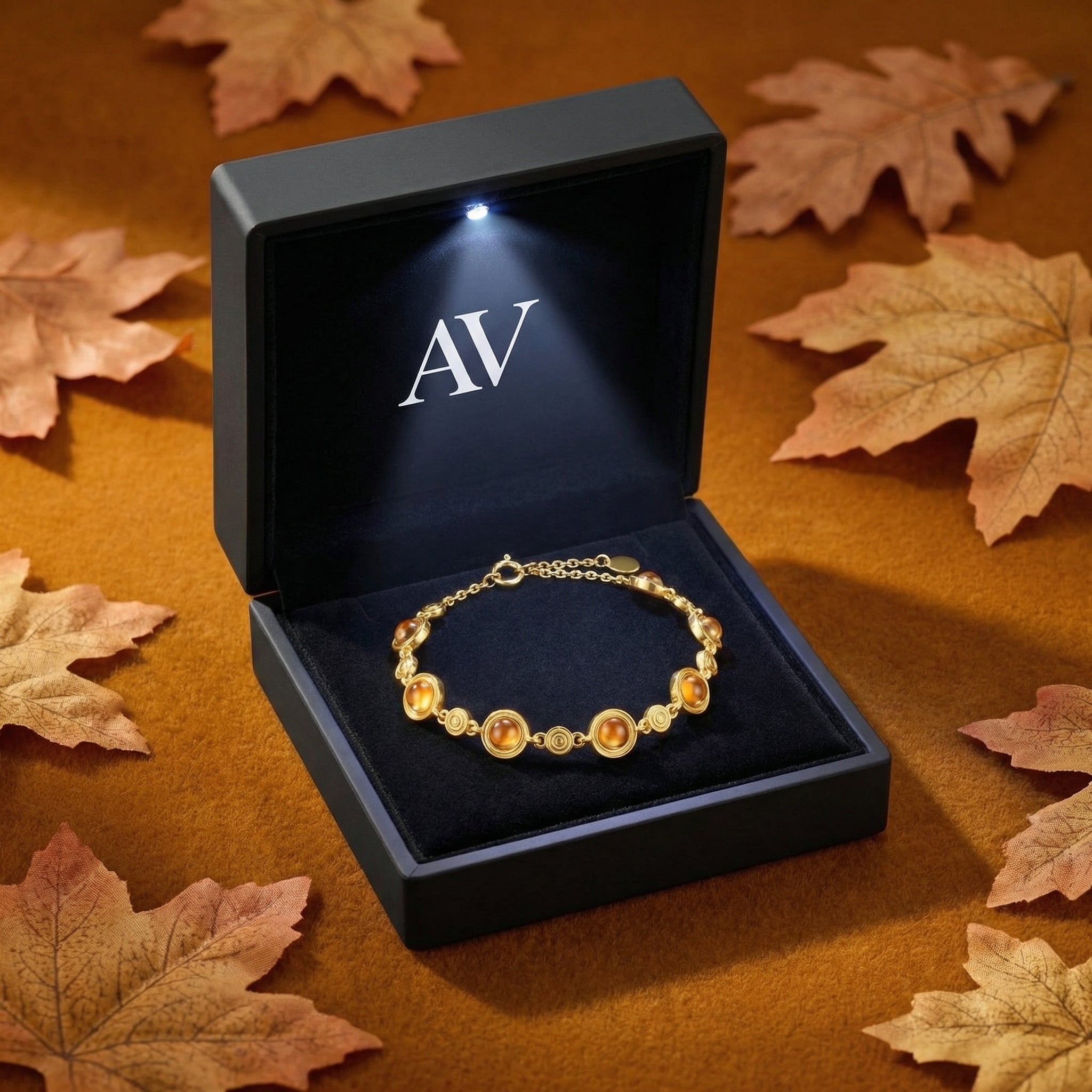 18K gold vermeil station bracelet inside a black LED-lit gift box surrounded by autumn leaves.