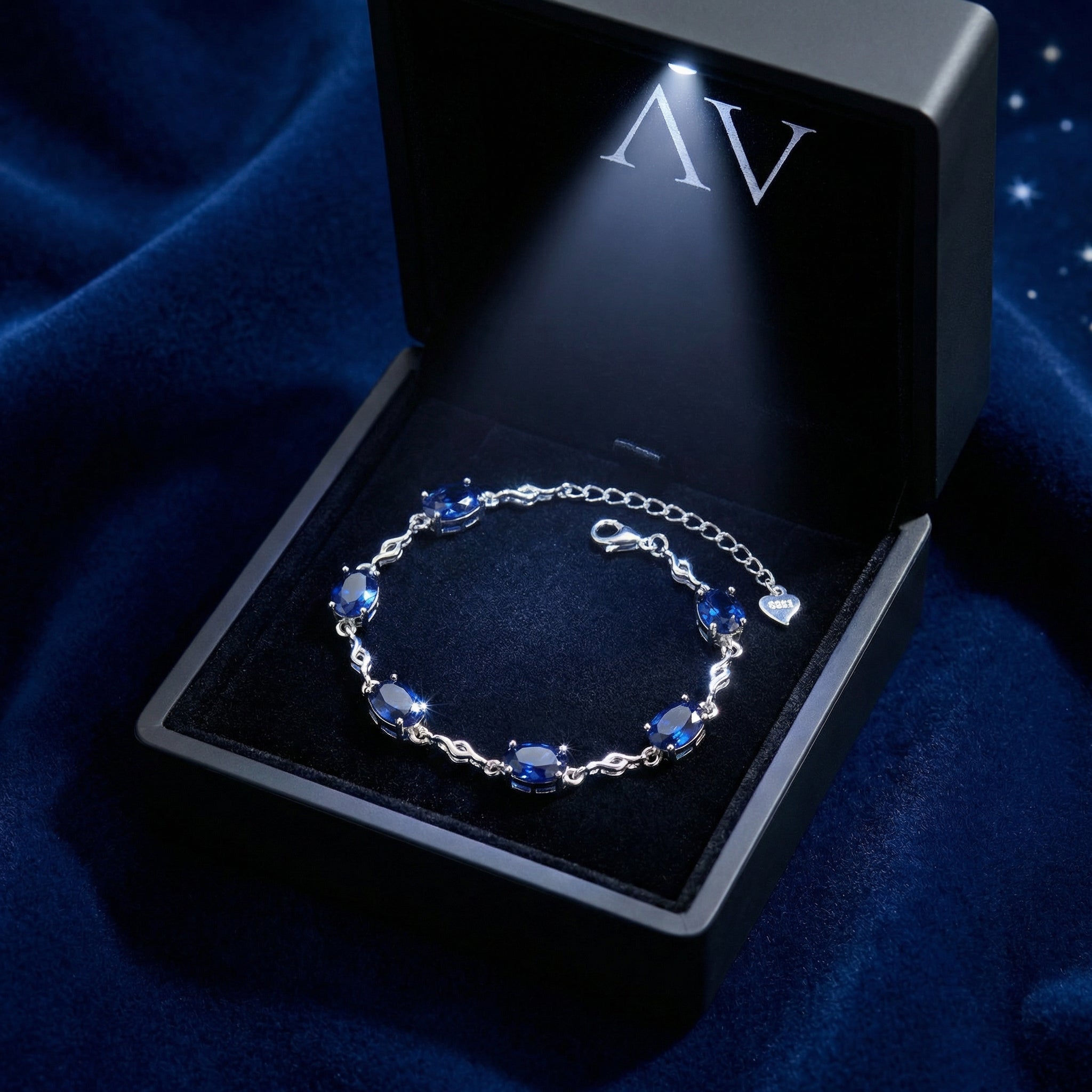S925 sterling silver sapphire station bracelet inside a lighted black jewelry gift box.
