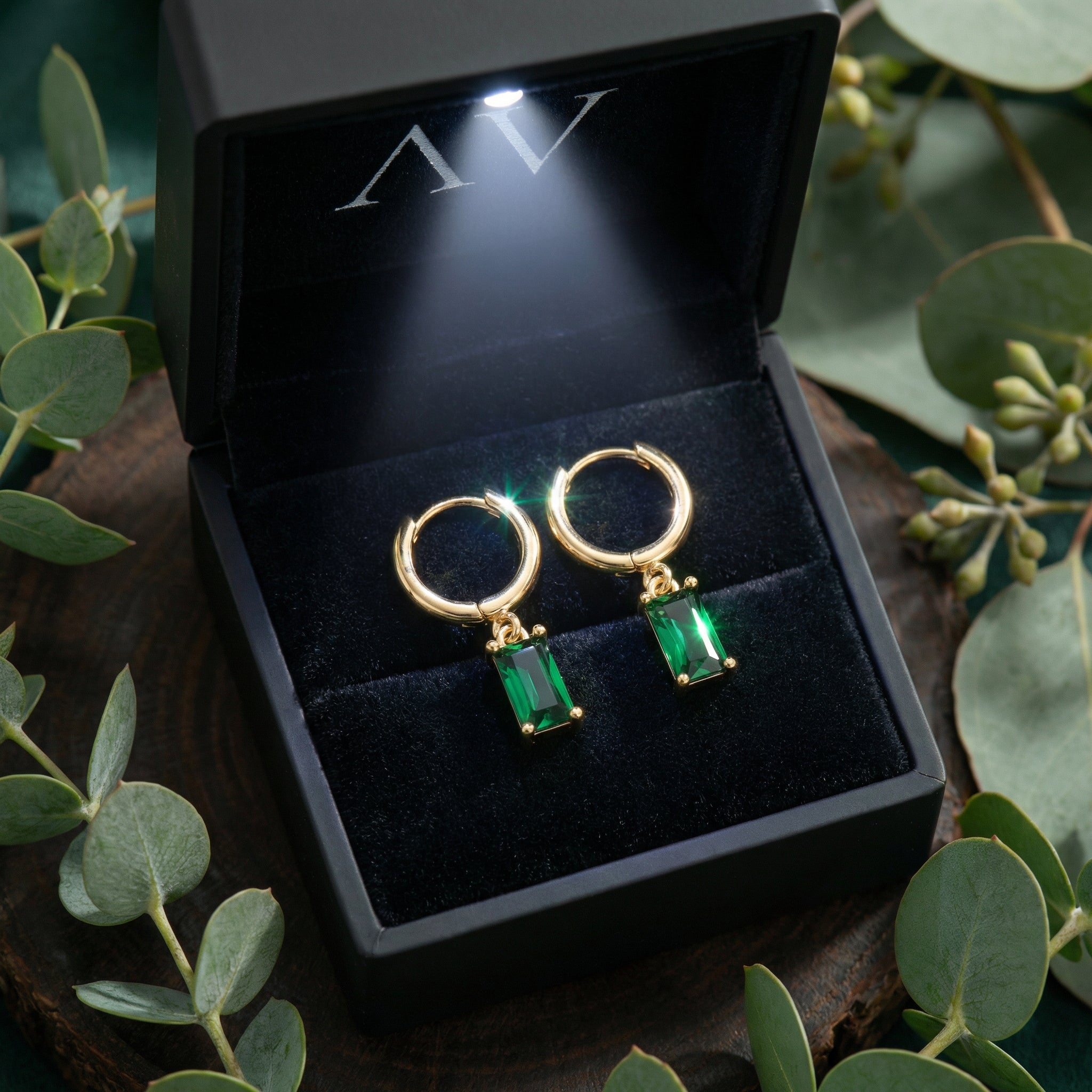 Gold vermeil emerald-cut drop earrings presented in a black jewelry box with a built-in LED light.