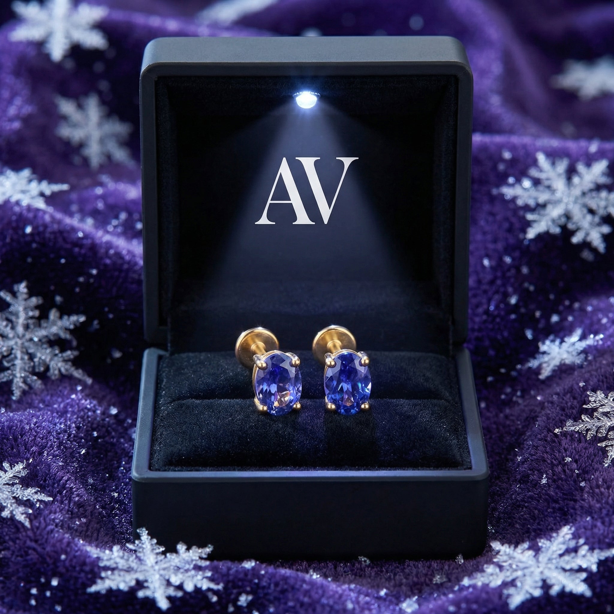 Oval cut simulated tanzanite gold vermeil earrings in a black LED-lit jewelry box on purple velvet.