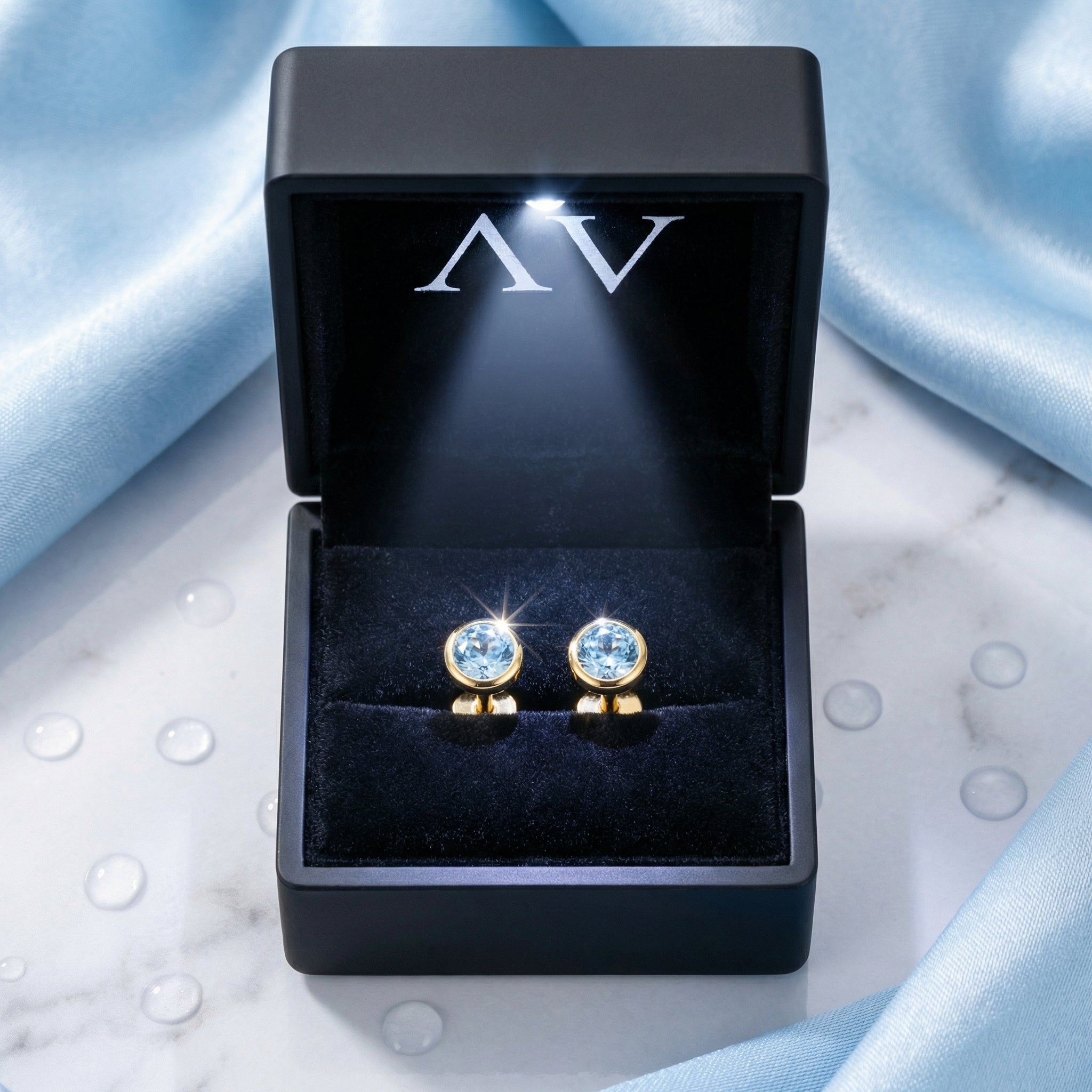 Round simulated aquamarine stud earrings in 18K gold vermeil inside a premium black LED-lighted gift box.