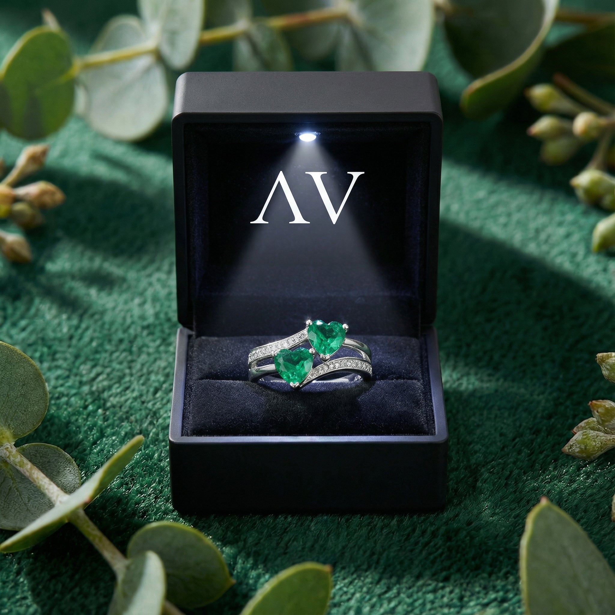 The Myrenis heart ring in a lighted black jewelry gift box on a green velvet and leaf background.
