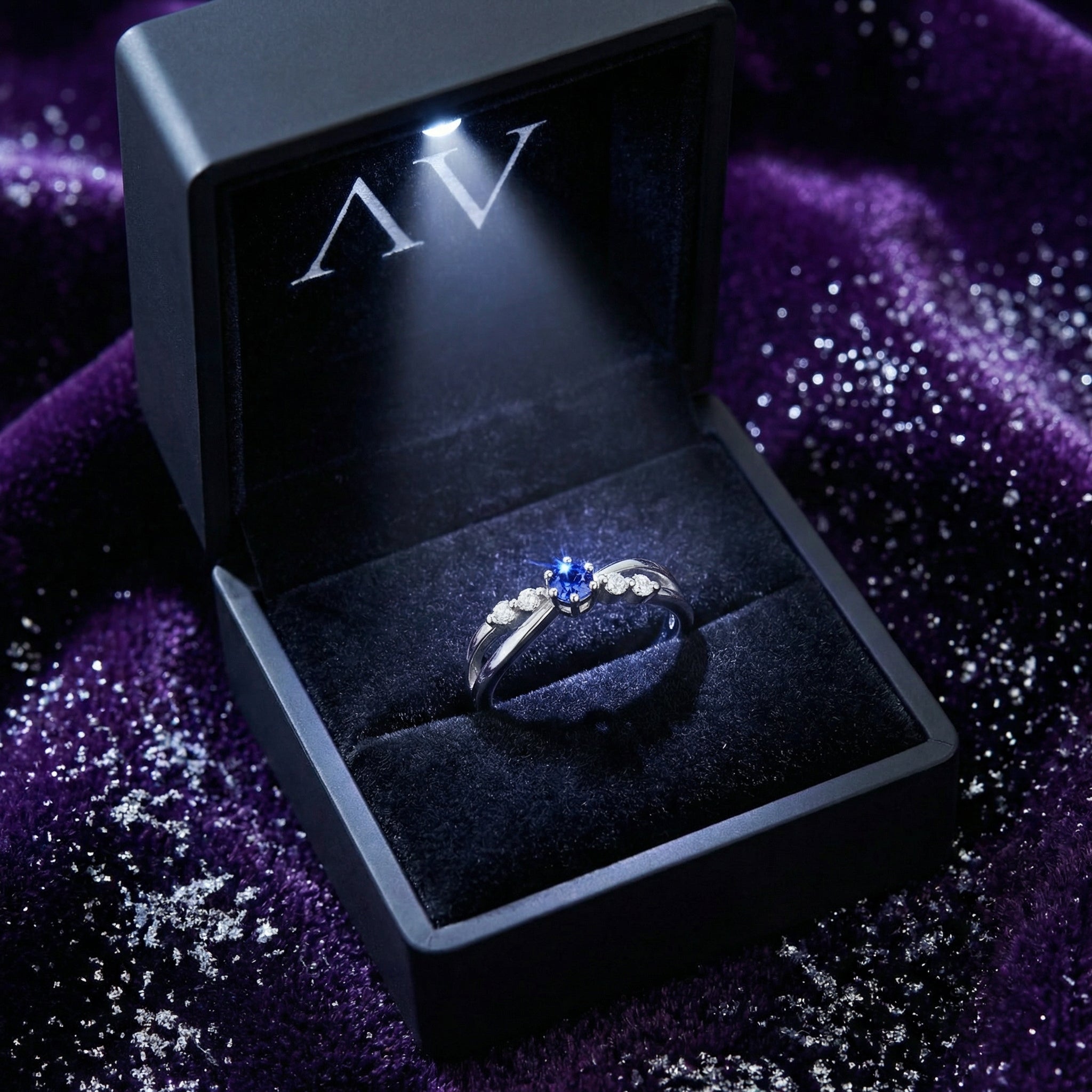 S925 sterling silver crossover ring with simulated tanzanite in a lighted black jewelry presentation box.