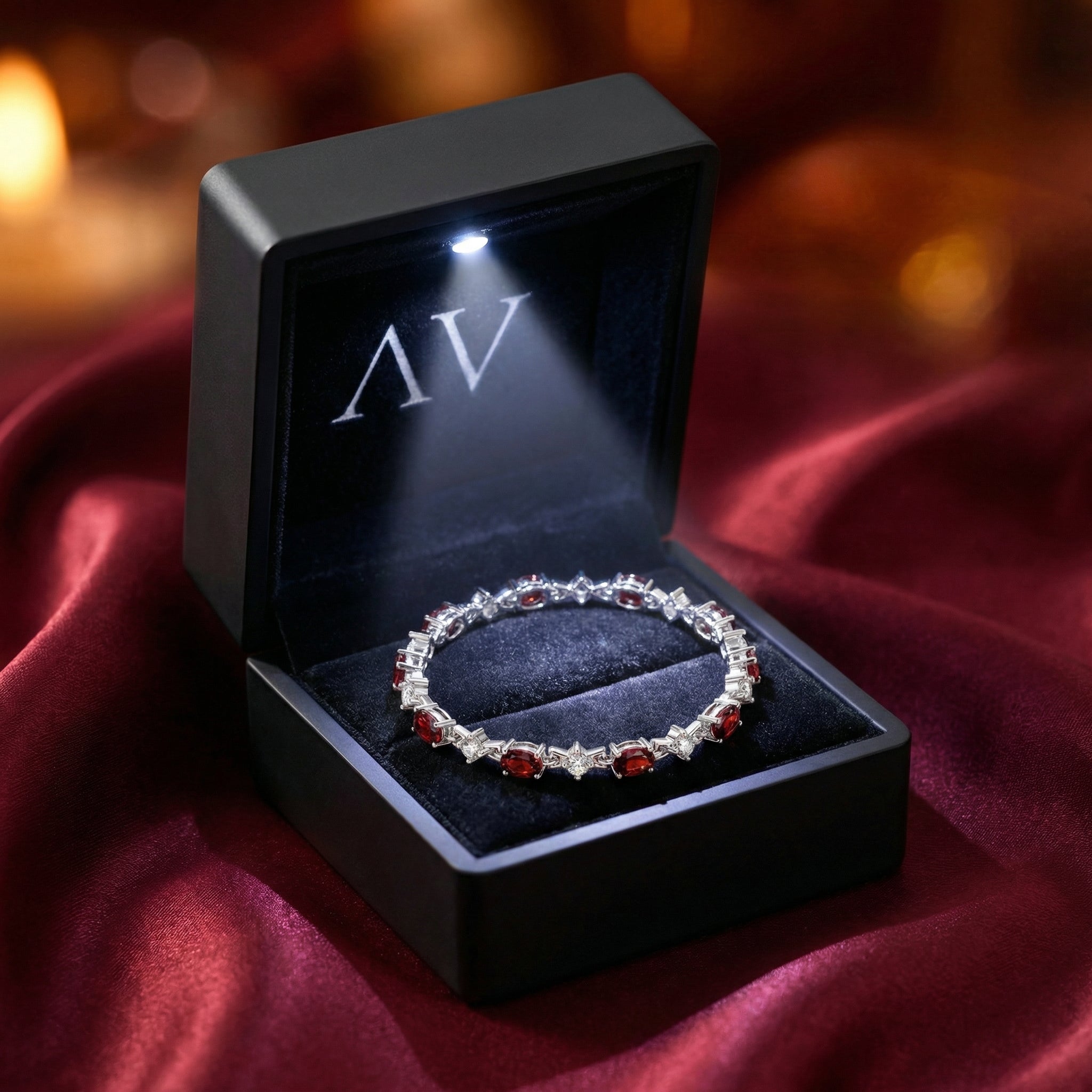 Sterling silver simulated garnet station bracelet inside a black LED-lighted gift box on red fabric.