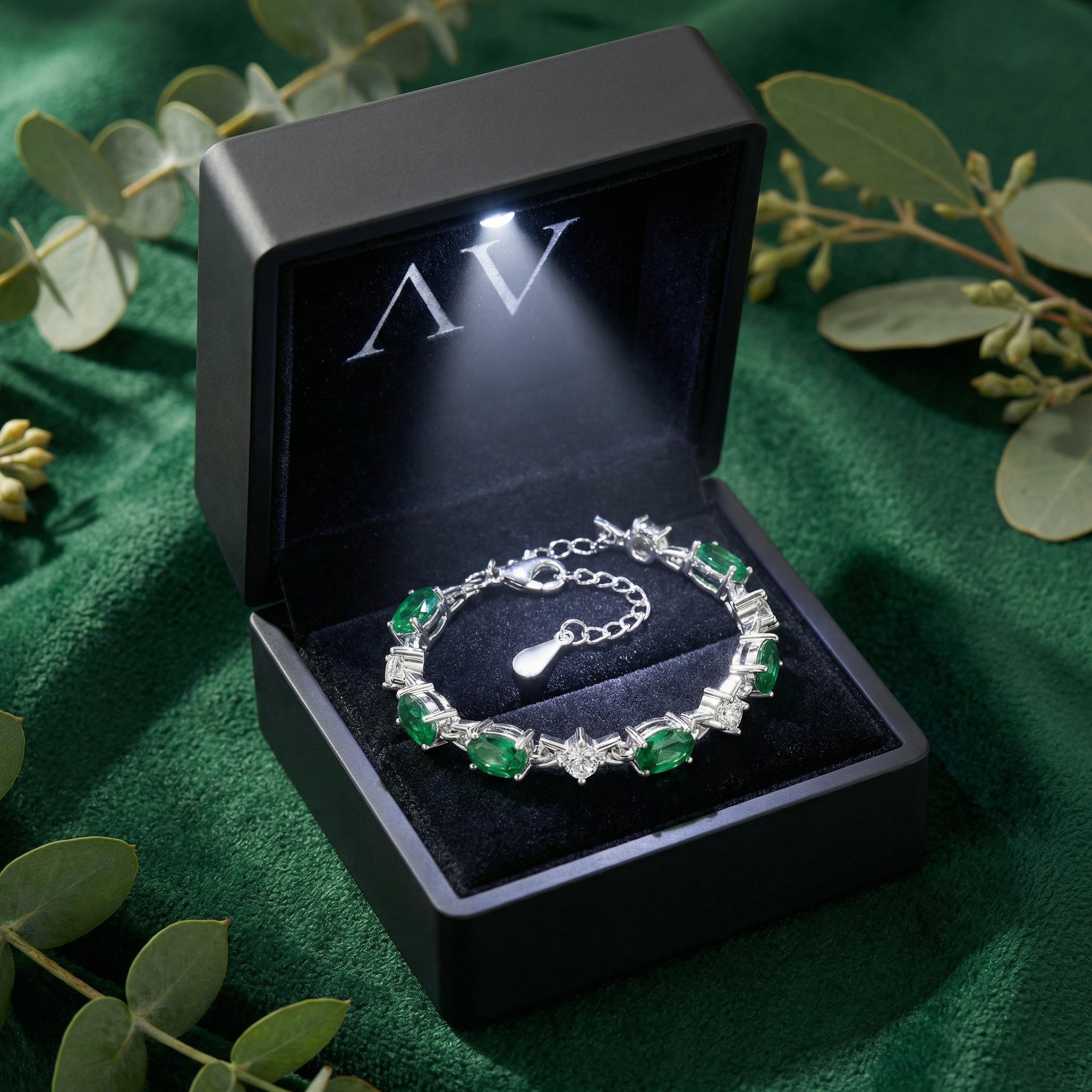 Silver oval simulated emerald bracelet presented in a black lighted jewelry gift box.