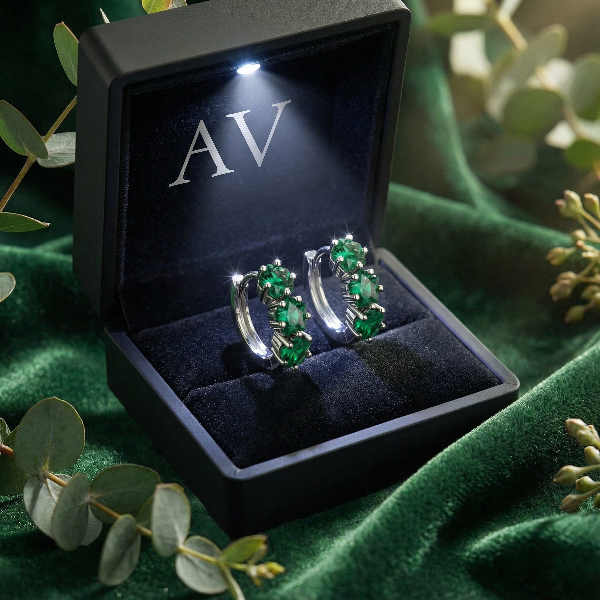 Triple star-cut simulated emerald sterling silver earrings inside a lighted black jewelry gift box.