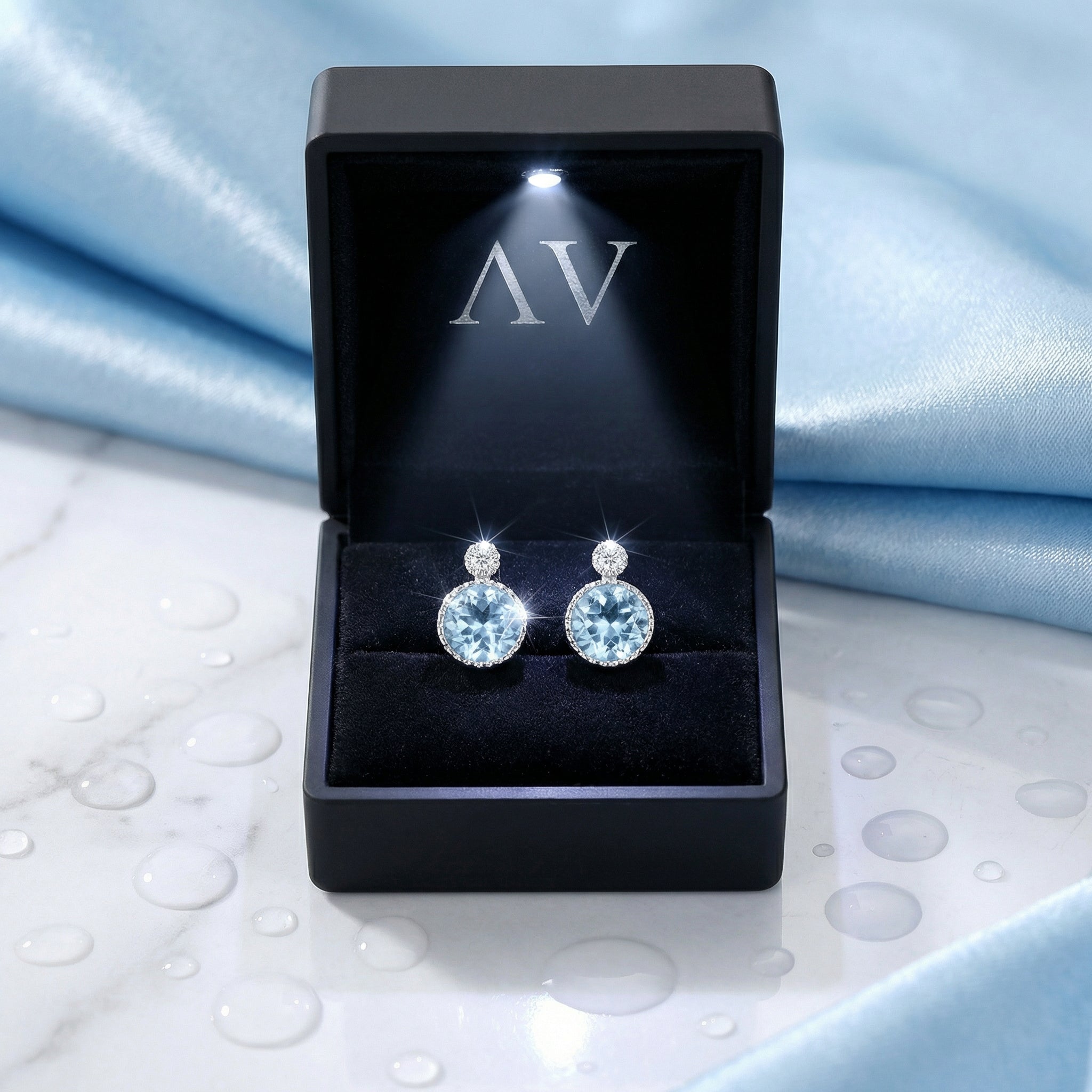 Simulated aquamarine sterling silver stud earrings in a black LED-lit presentation gift box.