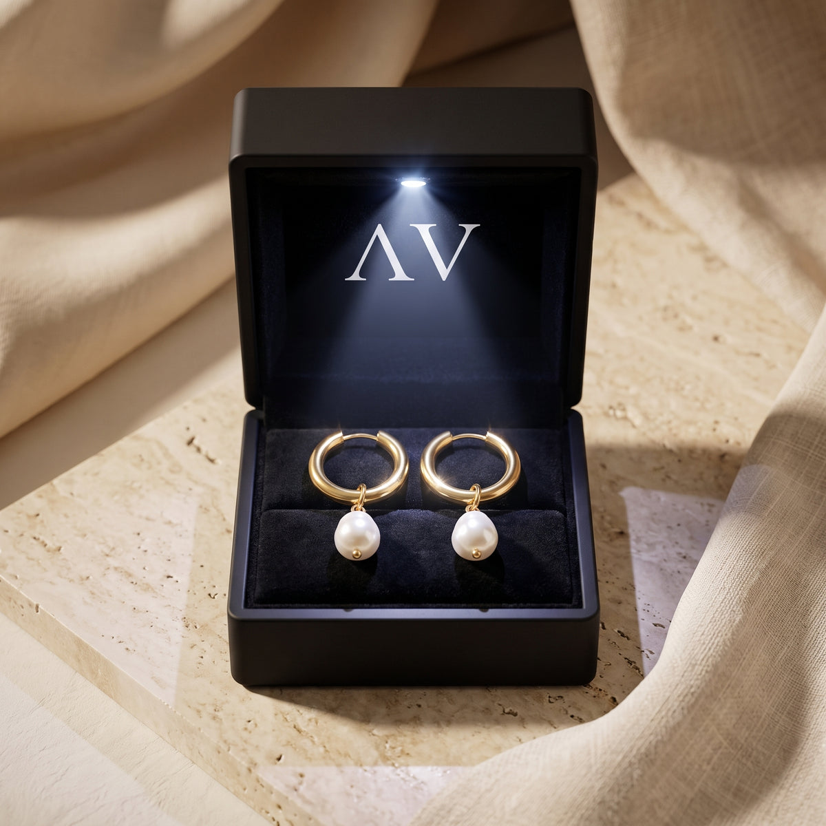 Gold pearl hoop earrings in an illuminated gift box.