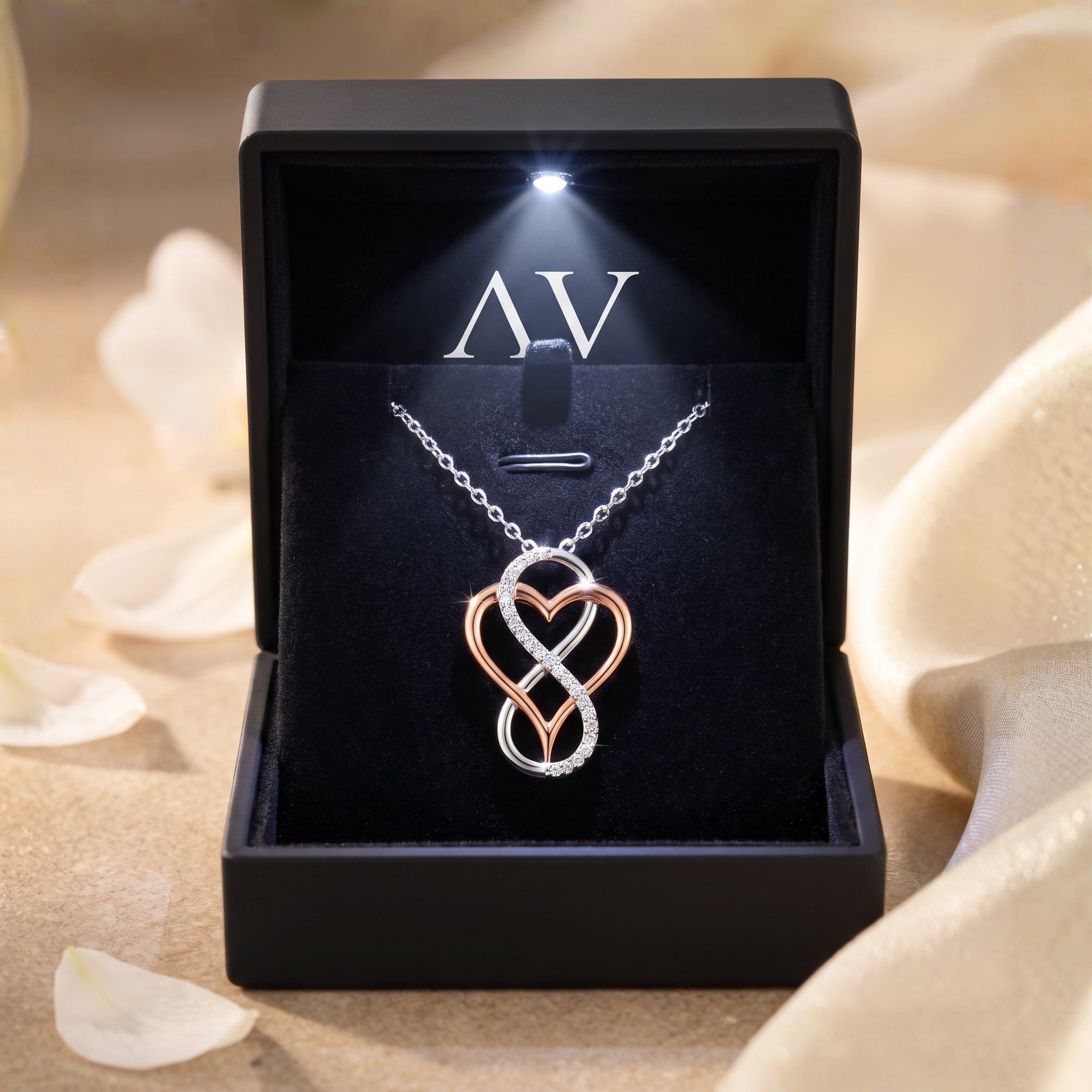 Two-tone infinity heart necklace displayed in a black LED-lit gift box.