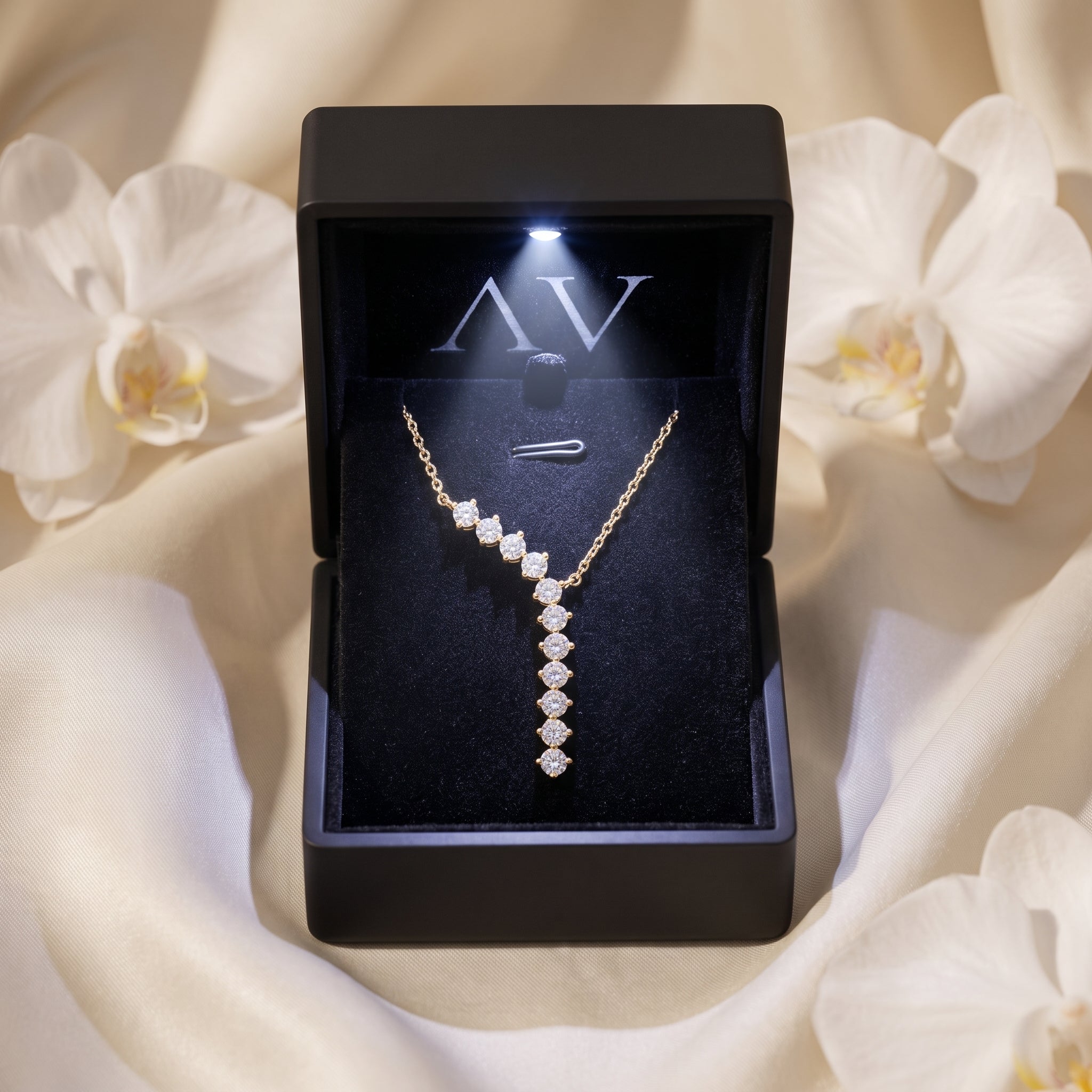 Gold curved drop moissanite necklace presented in a black LED-lit jewelry gift box.
