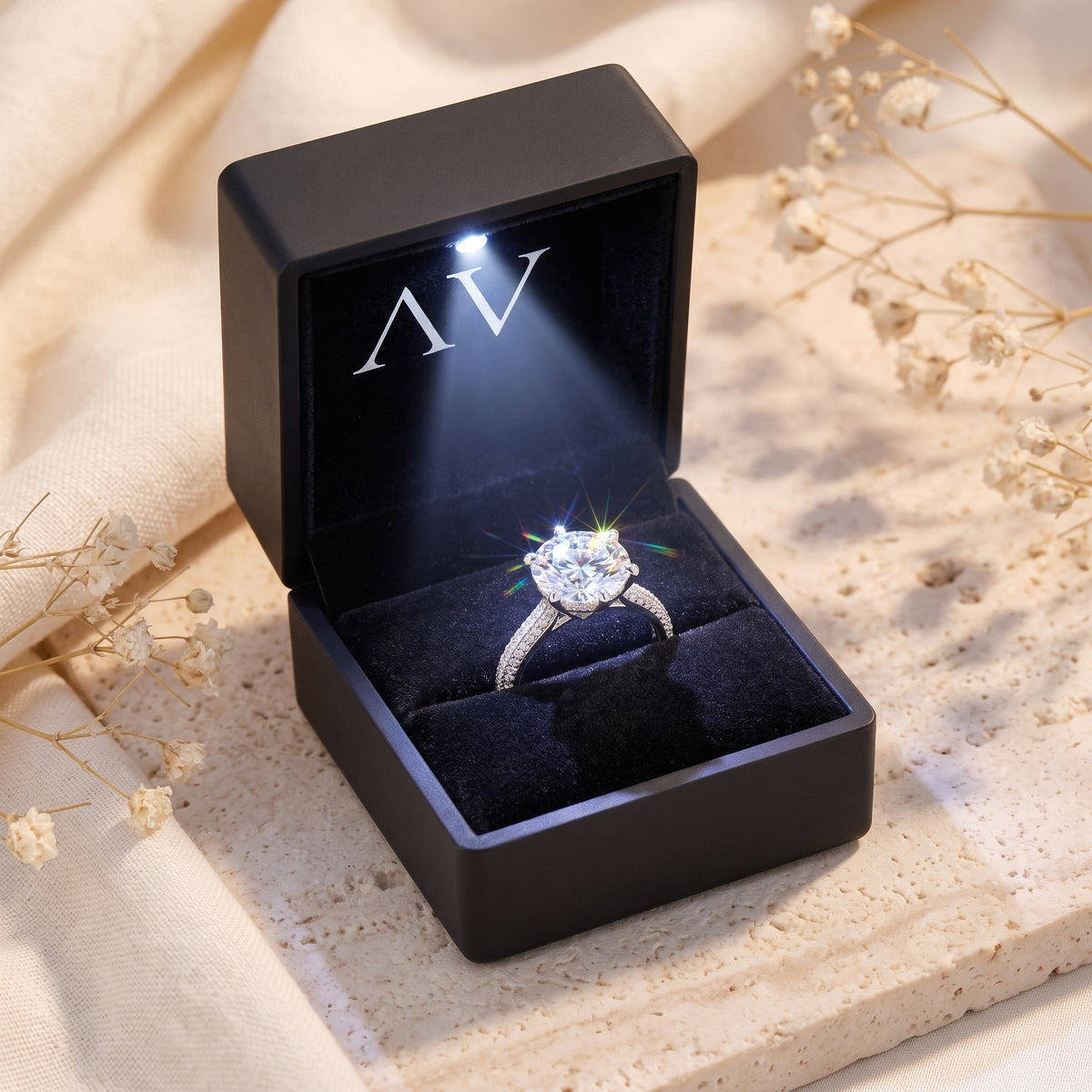 Silver solitaire ring inside a black LED-lit presentation box on a styled background.