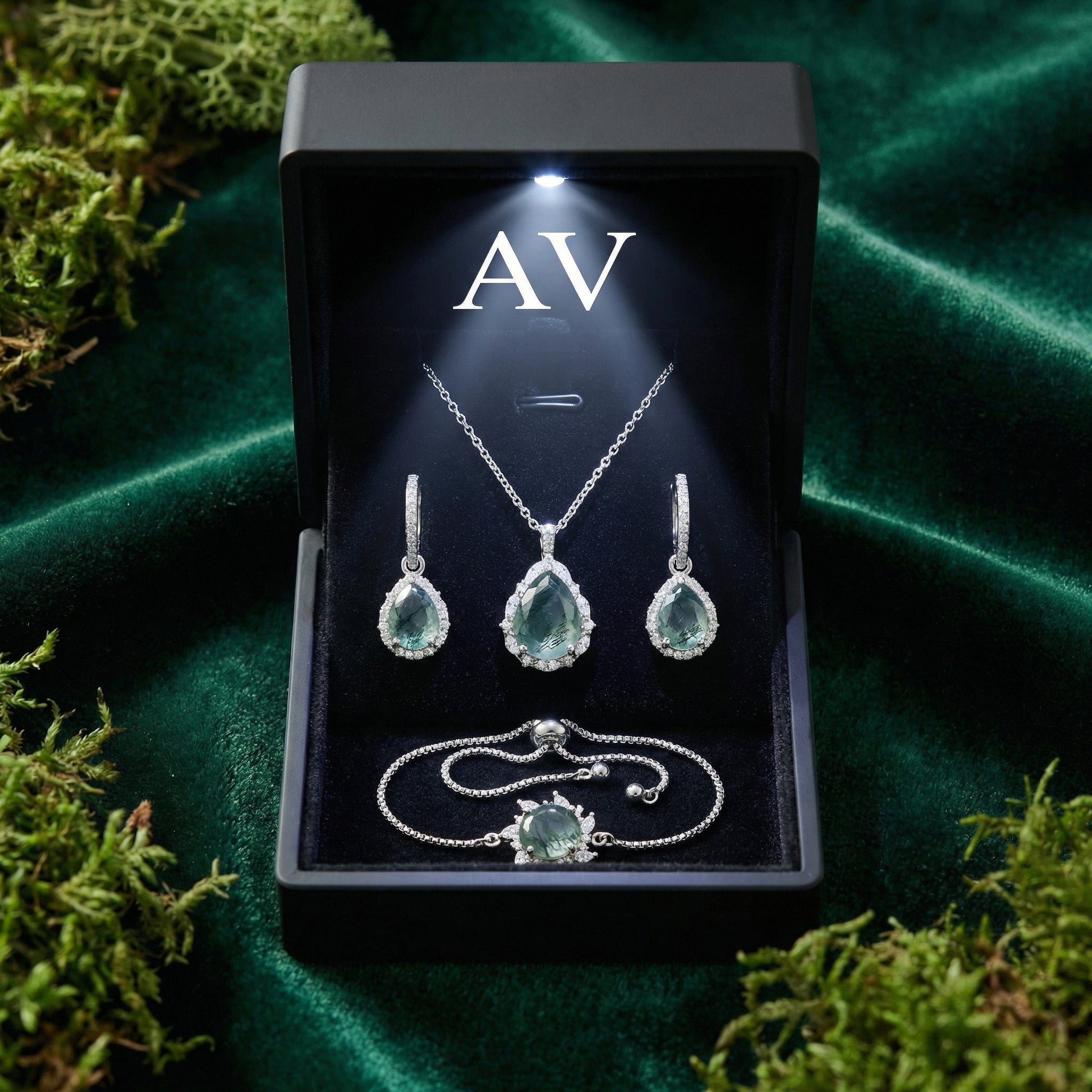 Moss Agate jewelry set presented in a lighted black gift box on a green velvet and moss background.