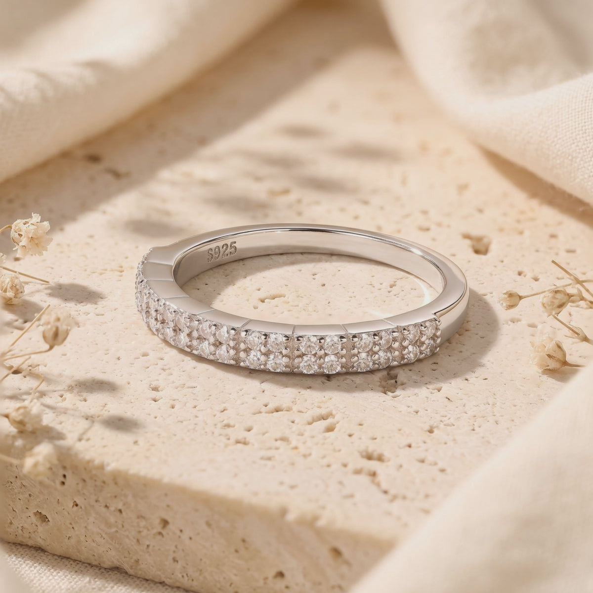 Rosalyssa silver double-row pavé ring displayed on a beige stone surface with an S925 hallmark visible inside.