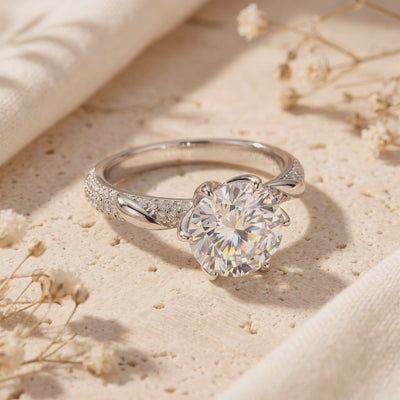 Neridelle ring resting on a light textured surface, showing its round center stone and twisted pavé band.