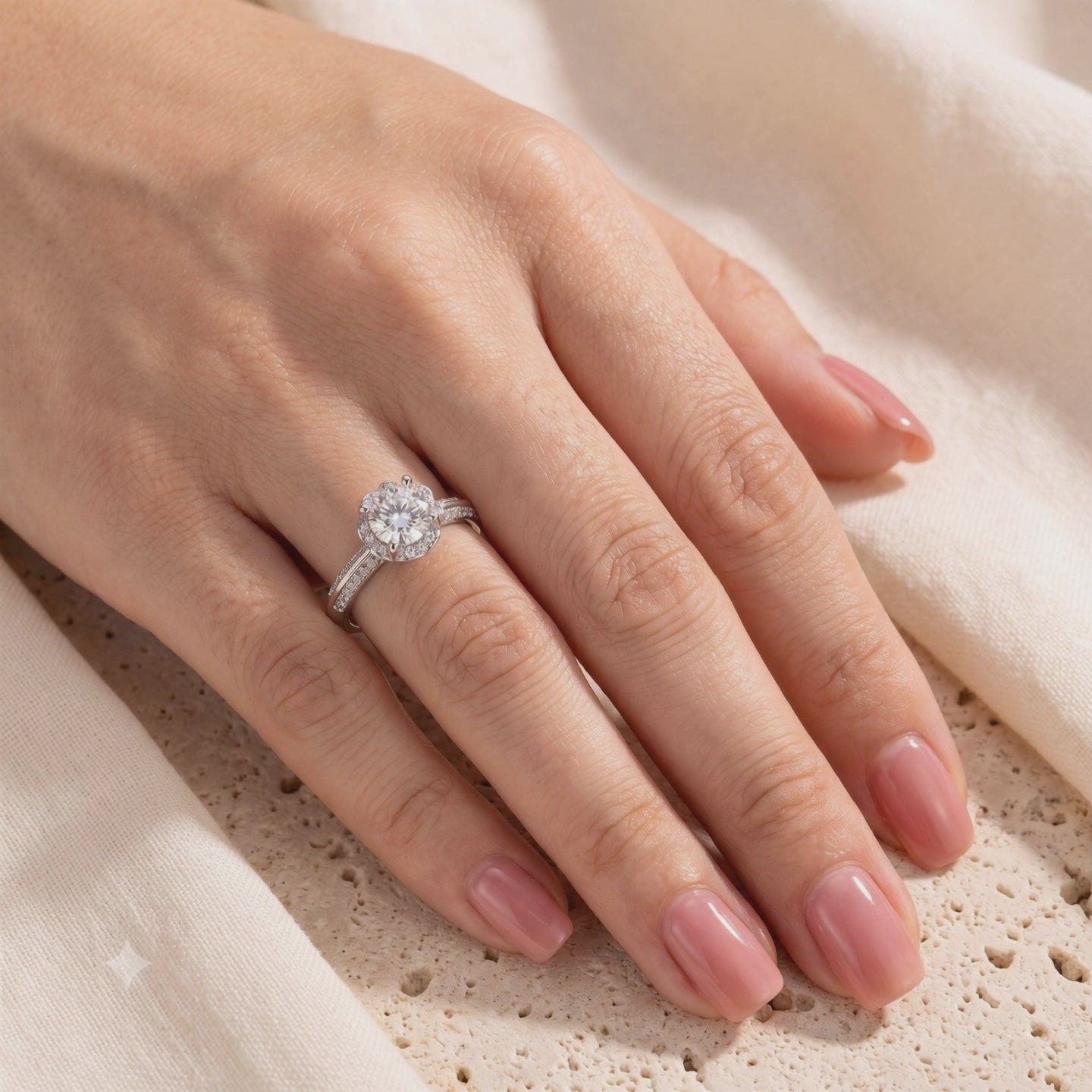 The Fleur Bloom Ring worn on a hand, showing its round center stone, flower-like halo, and pavé band.
